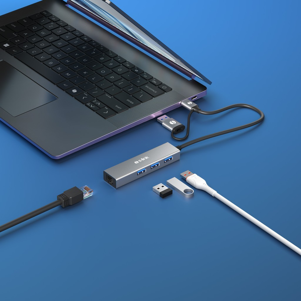 Gümüş USB-C hub, üç USB bağlantı noktası, dizüstü bilgisayar ve aksesuarlar yanında.