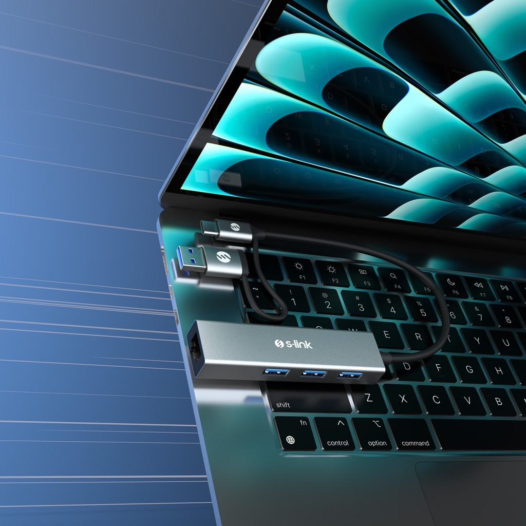Üç portlu gri bir USB-C hub gümüş bir dizüstü bilgisayara bağlı.