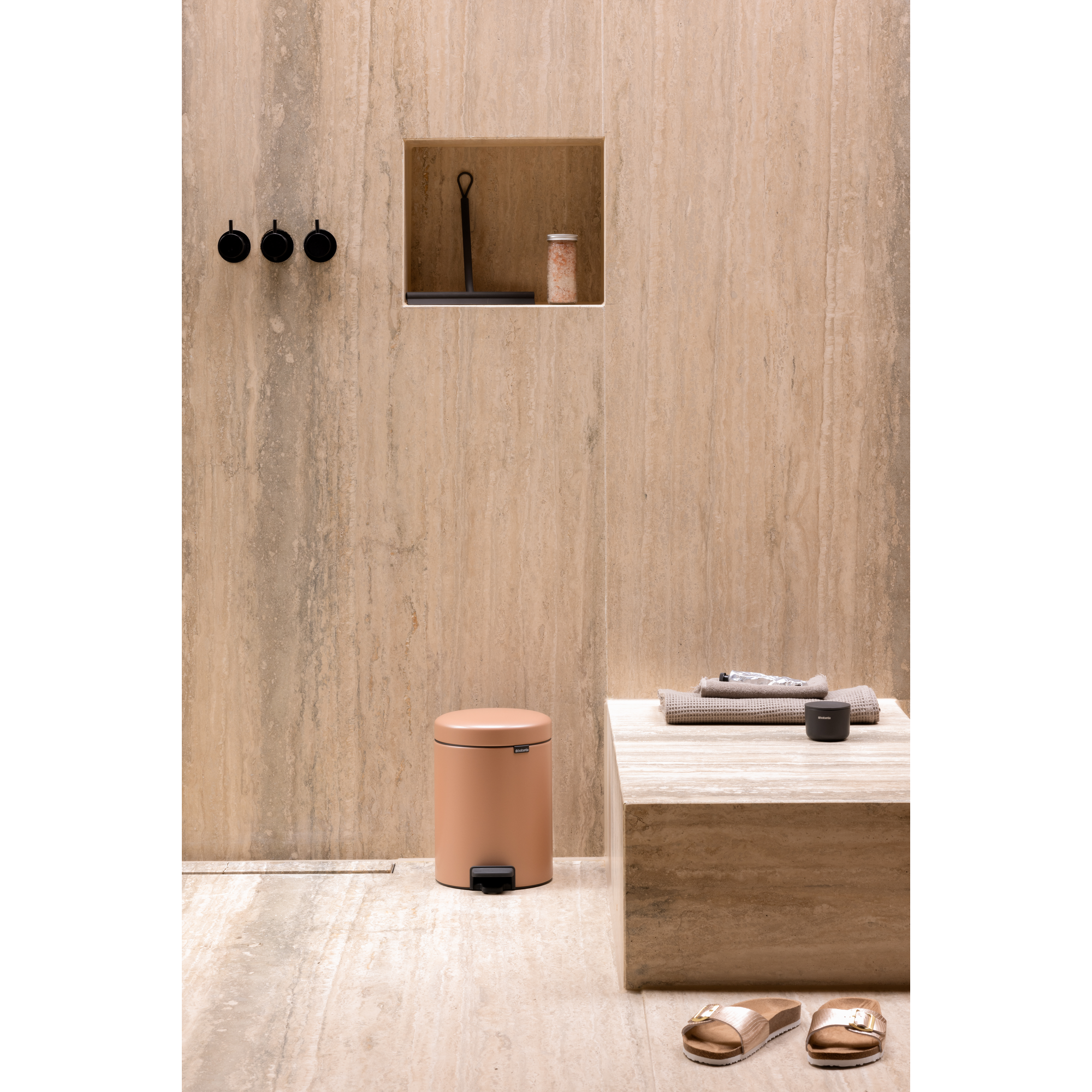 Badkamer met douche, prullenbak, handdoeken en sandalen.