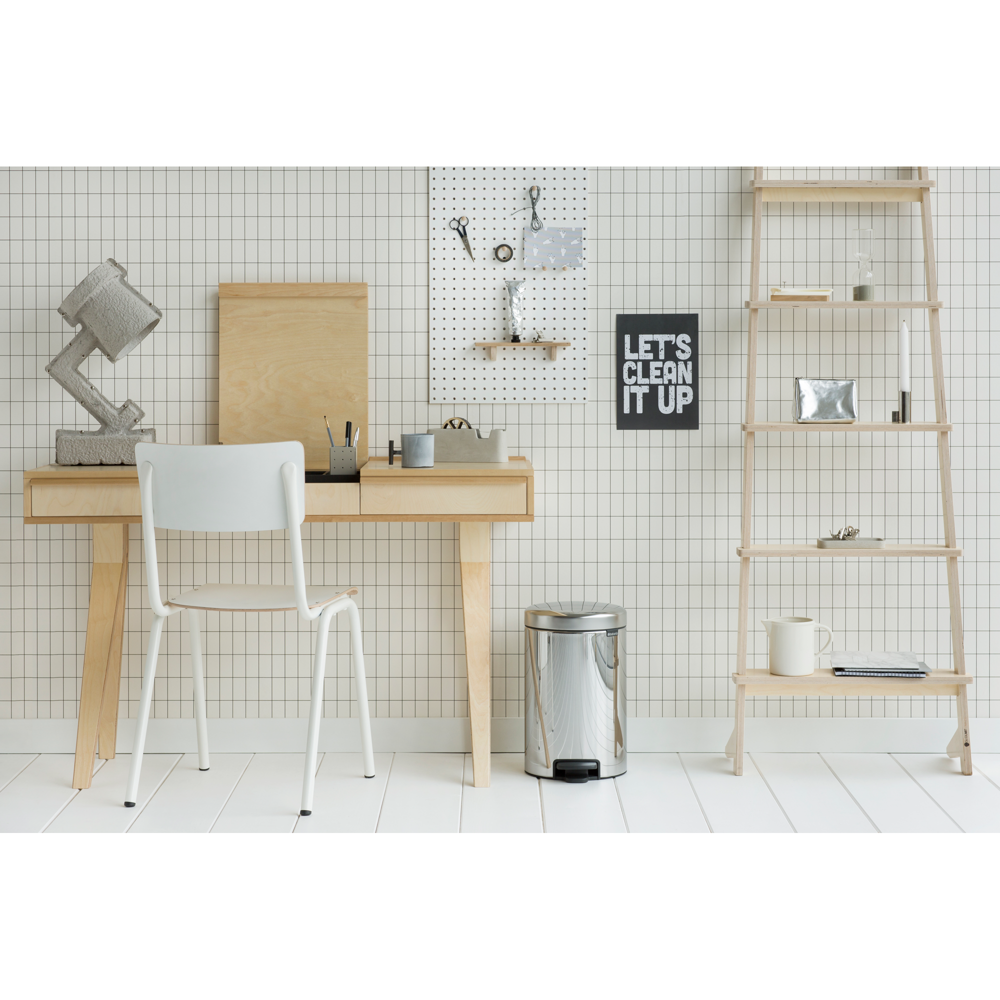 Minimalistische bureau met stoel, lamp en pegboard tegen een rastermuur.