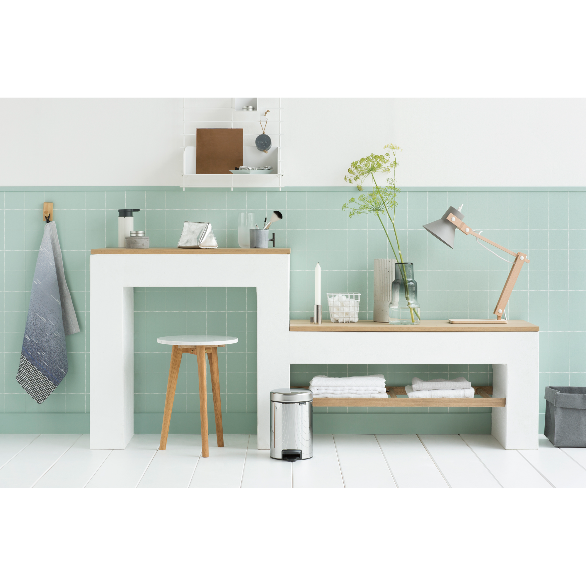 Een badkamer met lichtgroene tegels, wit meubilair en houten accenten.