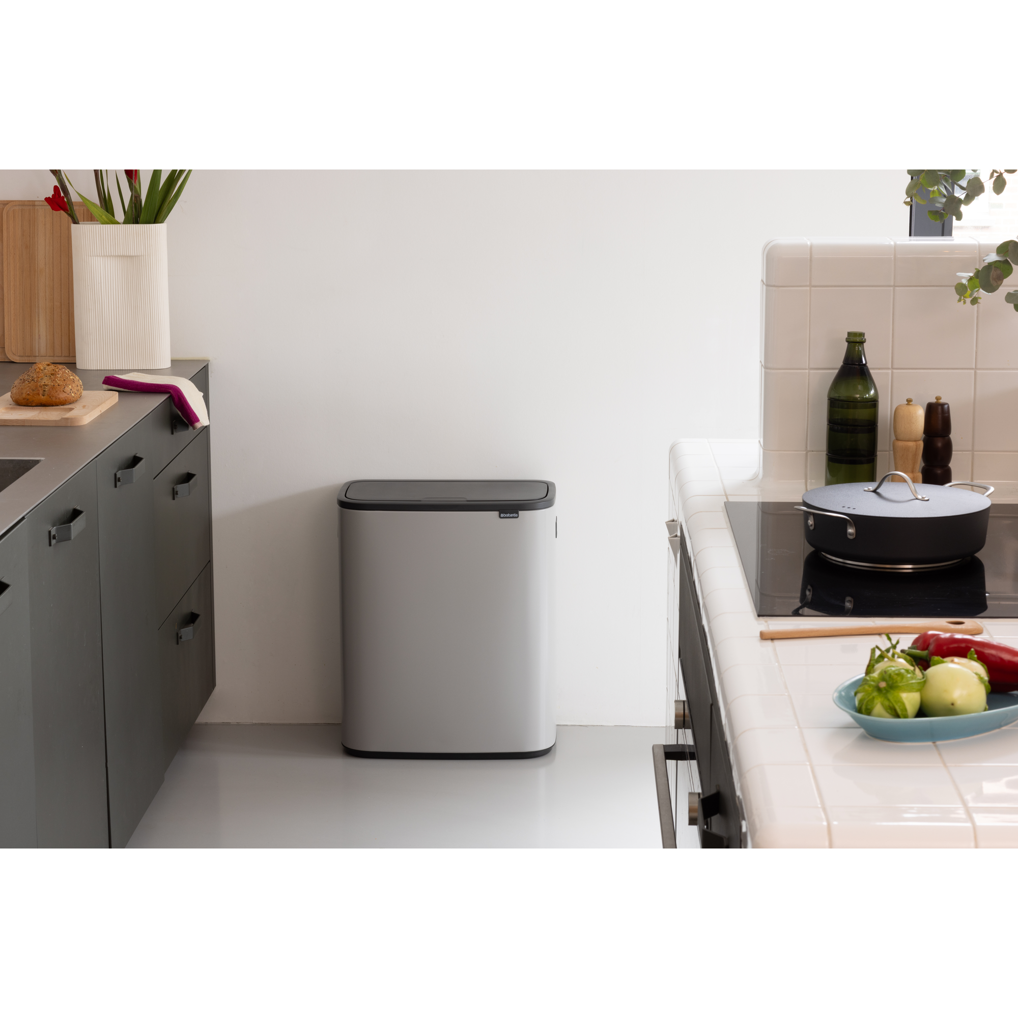 Moderne keuken met prullenbak, fornuis en fruit op het aanrecht.
