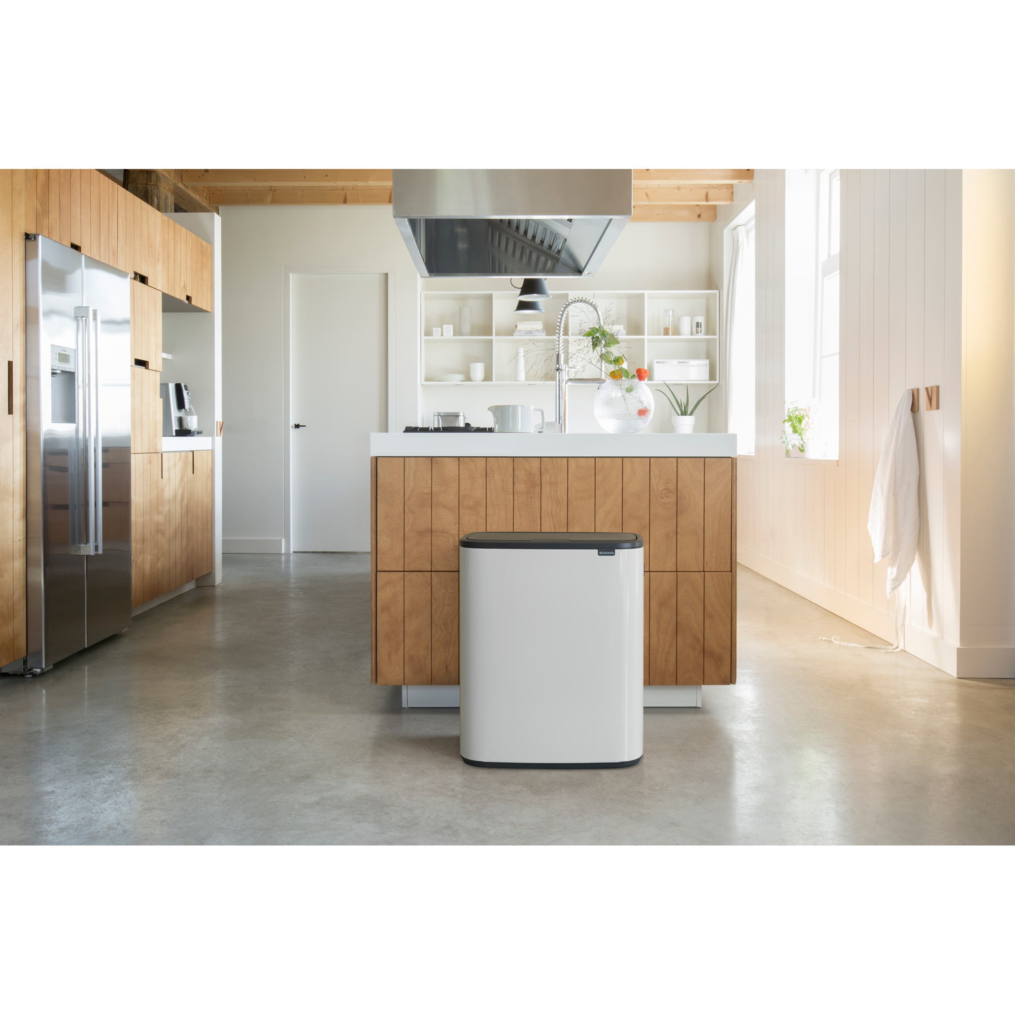 Moderne keuken met houten kasten, roestvrijstalen apparaten en een witte prullenbak.