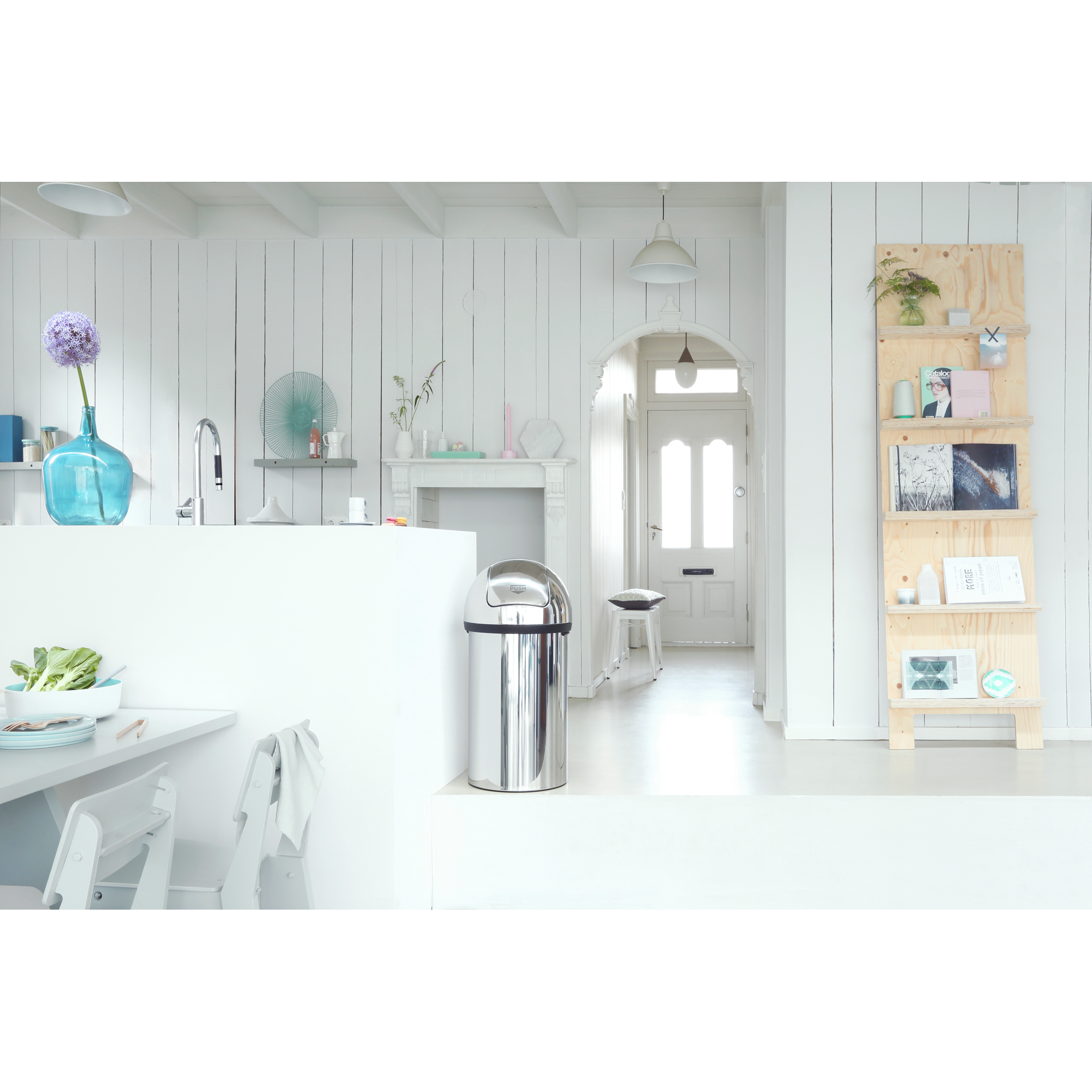 Licht, modern interieur met keukeneiland, prullenbak en deuropening.