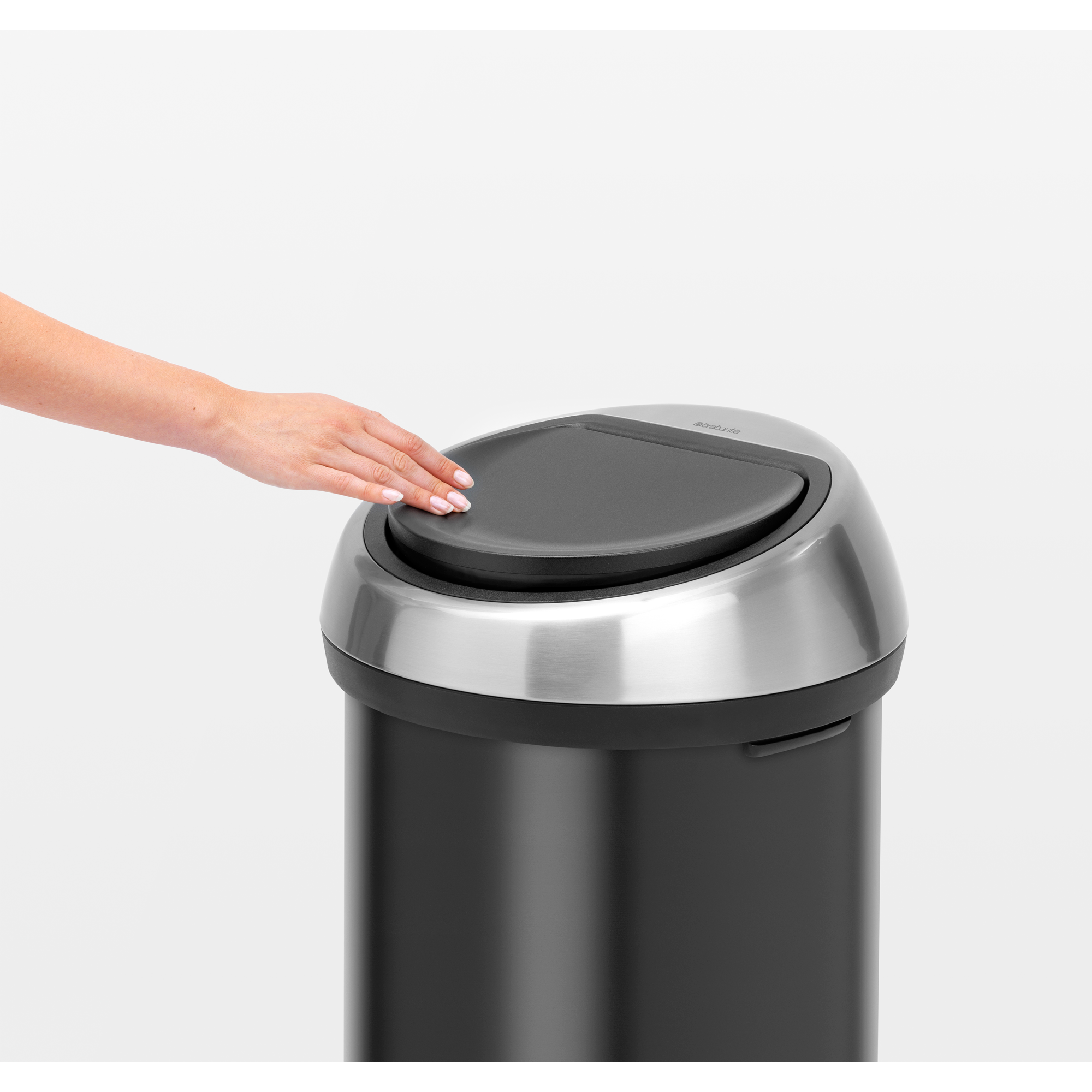 Een hand raakt het deksel van een zwarte prullenbak met zilveren rand aan.