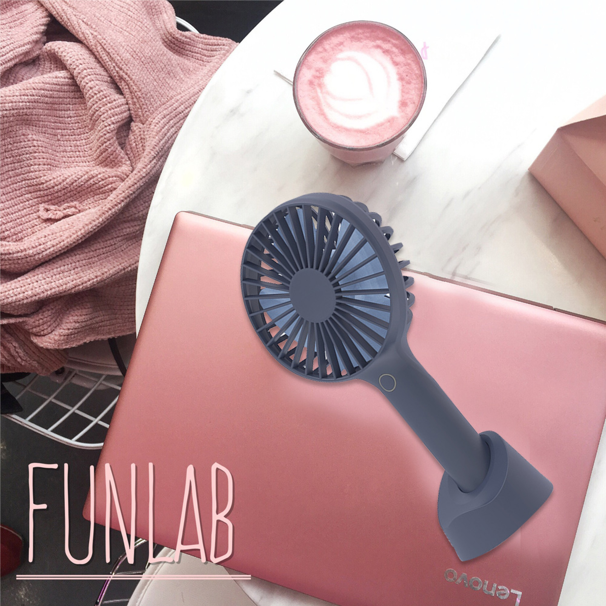 Ein rosafarbenes Laptop mit einem blauen Ventilator, einer Tasse Kaffee und einem Pullover.