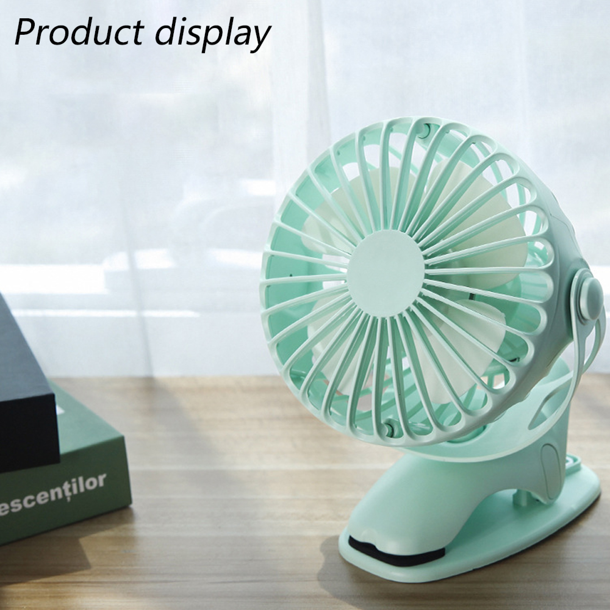 Ein kleiner mintgrüner Ventilator mit Clip-Basis steht auf einem Holztisch.