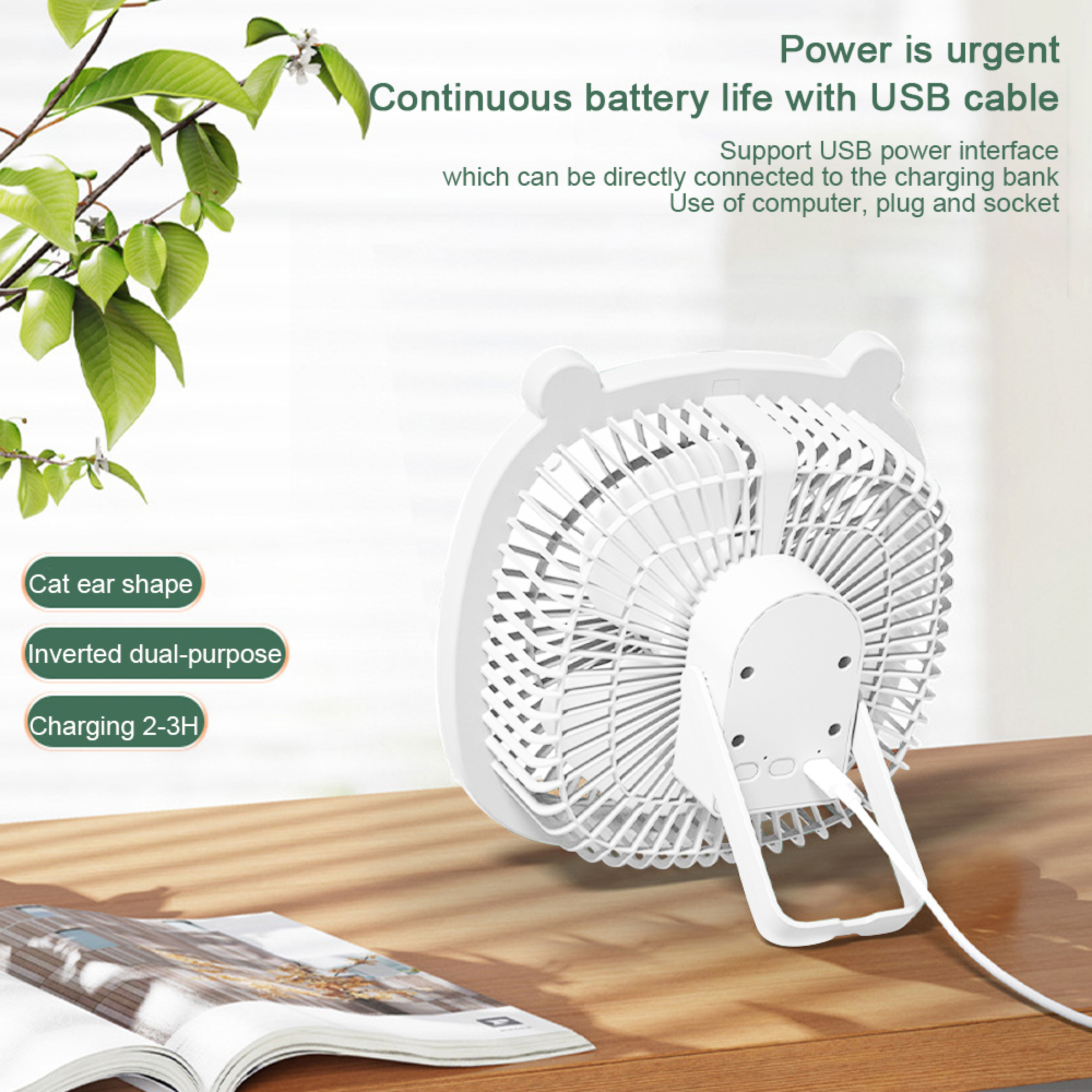 Weißer Katzenohr-Ventilator mit USB-Kabel auf einem Holztisch neben einem offenen Buch.