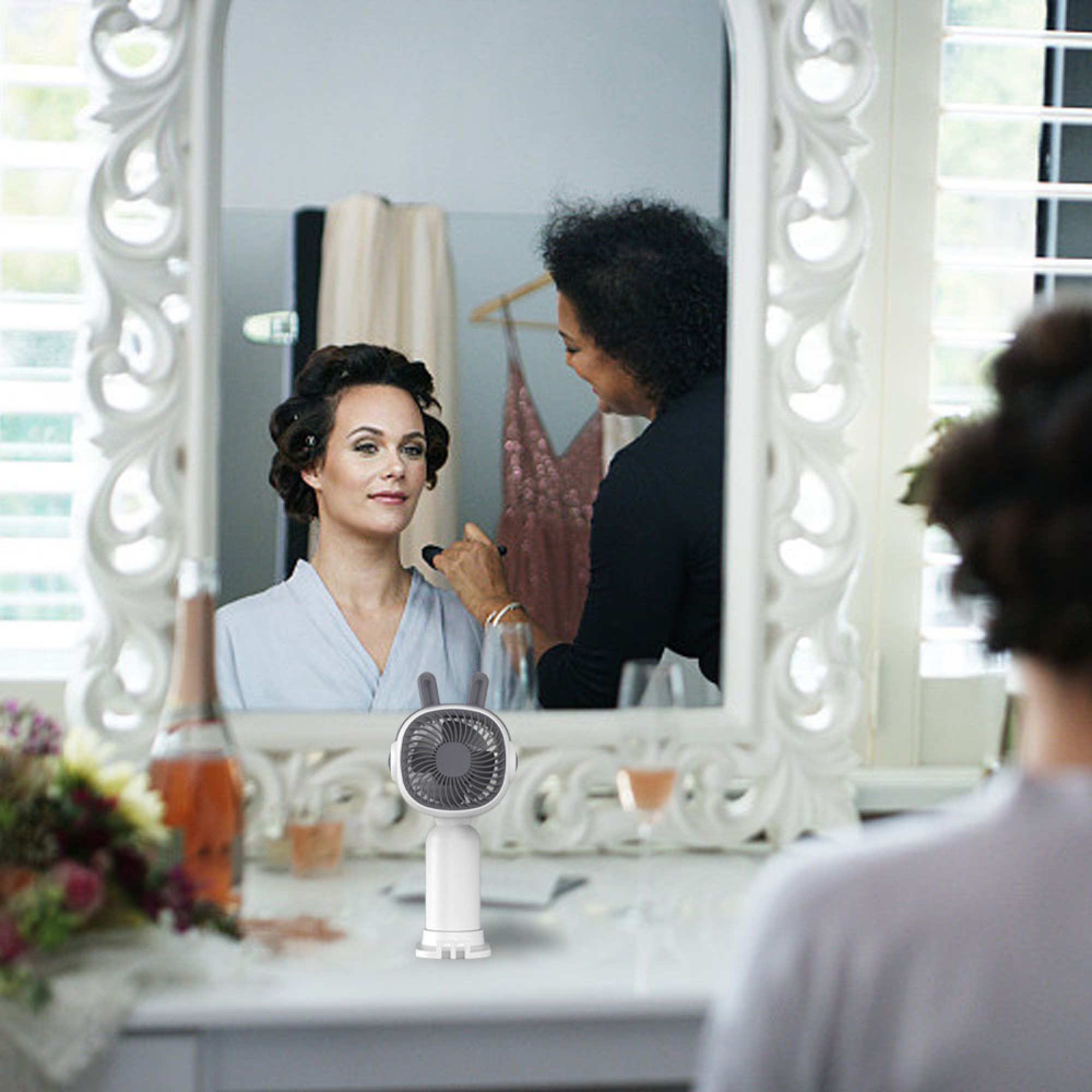 Eine Frau bekommt Make-up aufgetragen, während sie sich in einem Spiegel betrachtet.