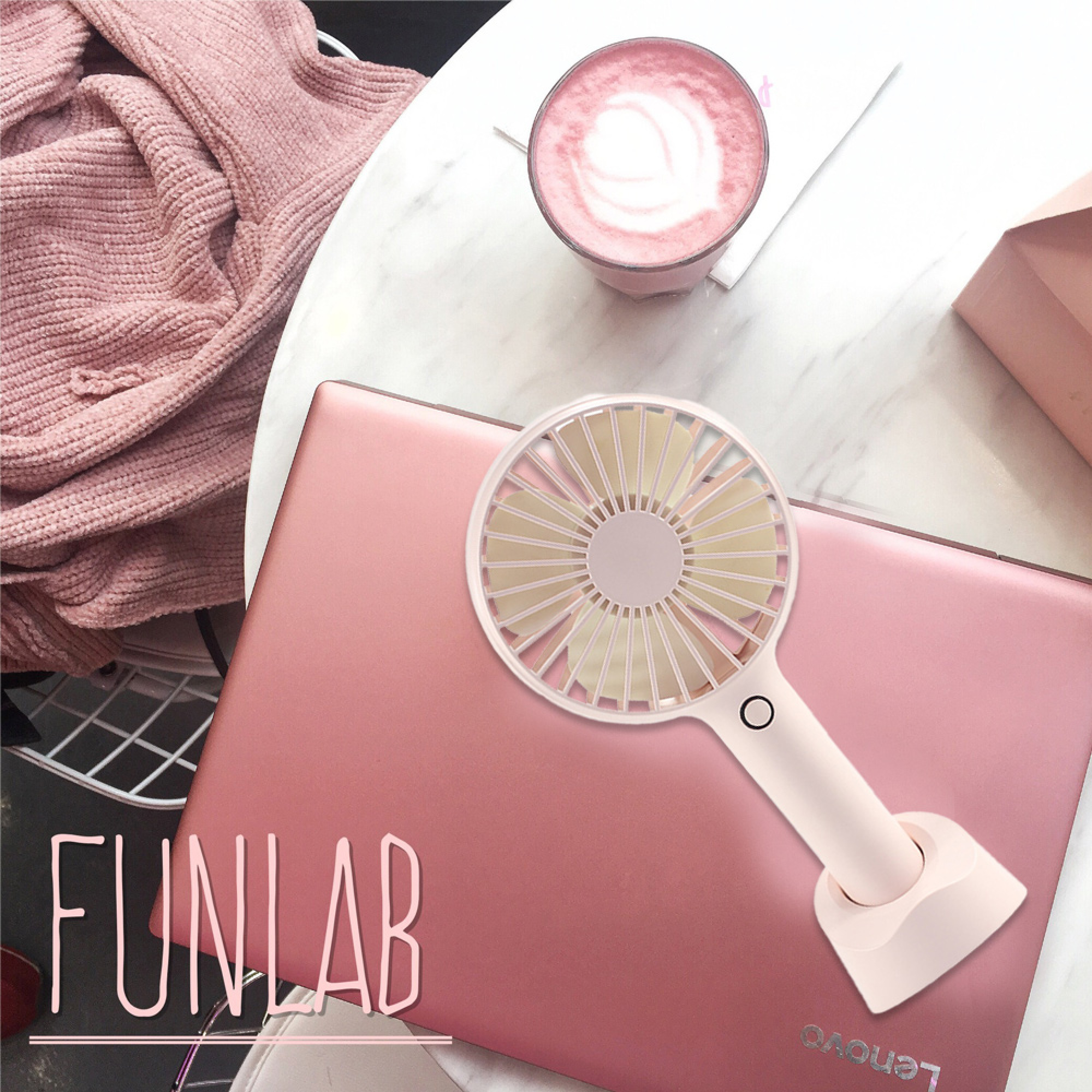 Ein rosafarbener Laptop mit einem kleinen Ventilator und einer rosa Kaffeetasse.