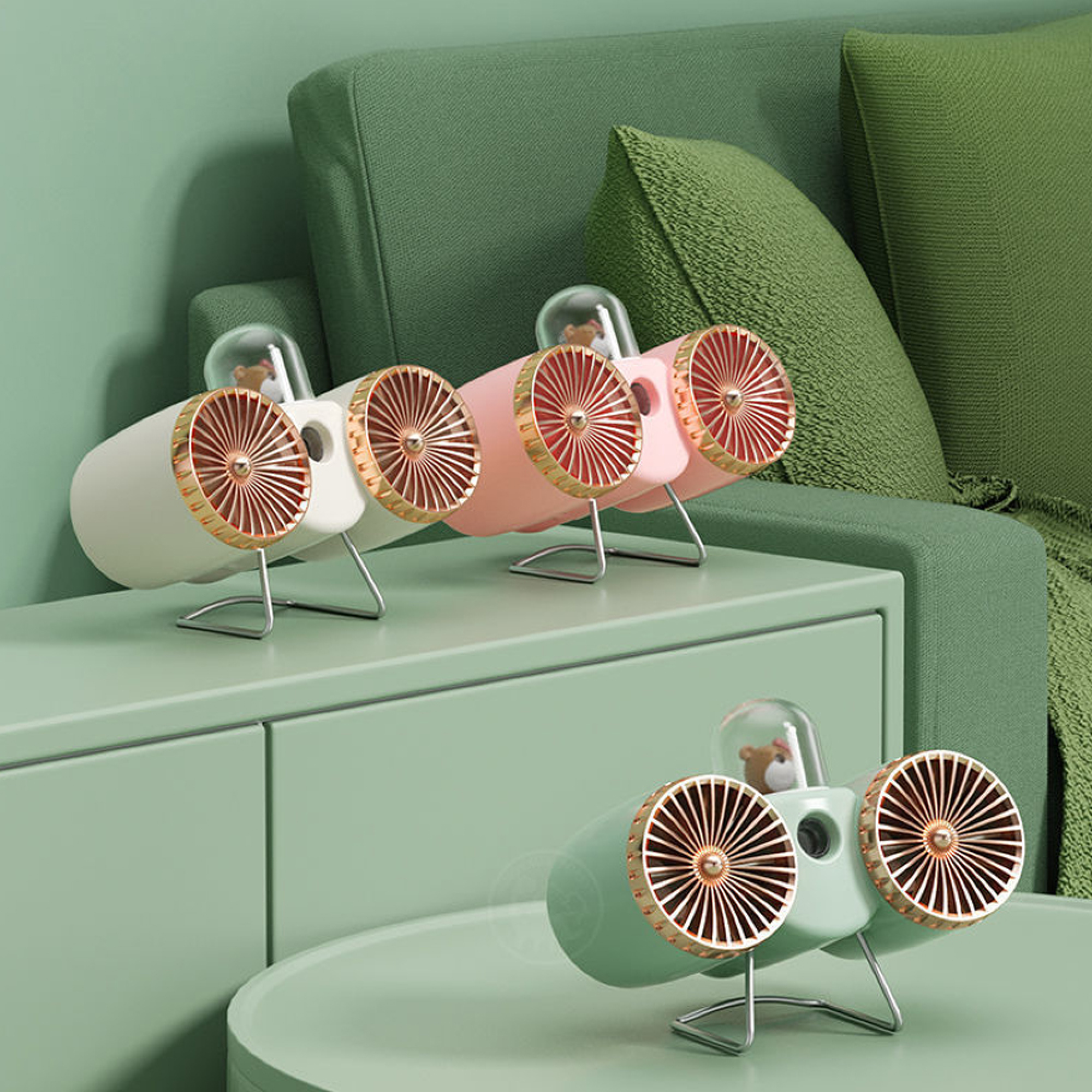 Drei Mini-Ventilatoren in Pastellfarben stehen auf einem grünen Regal, dahinter ein Sofa.