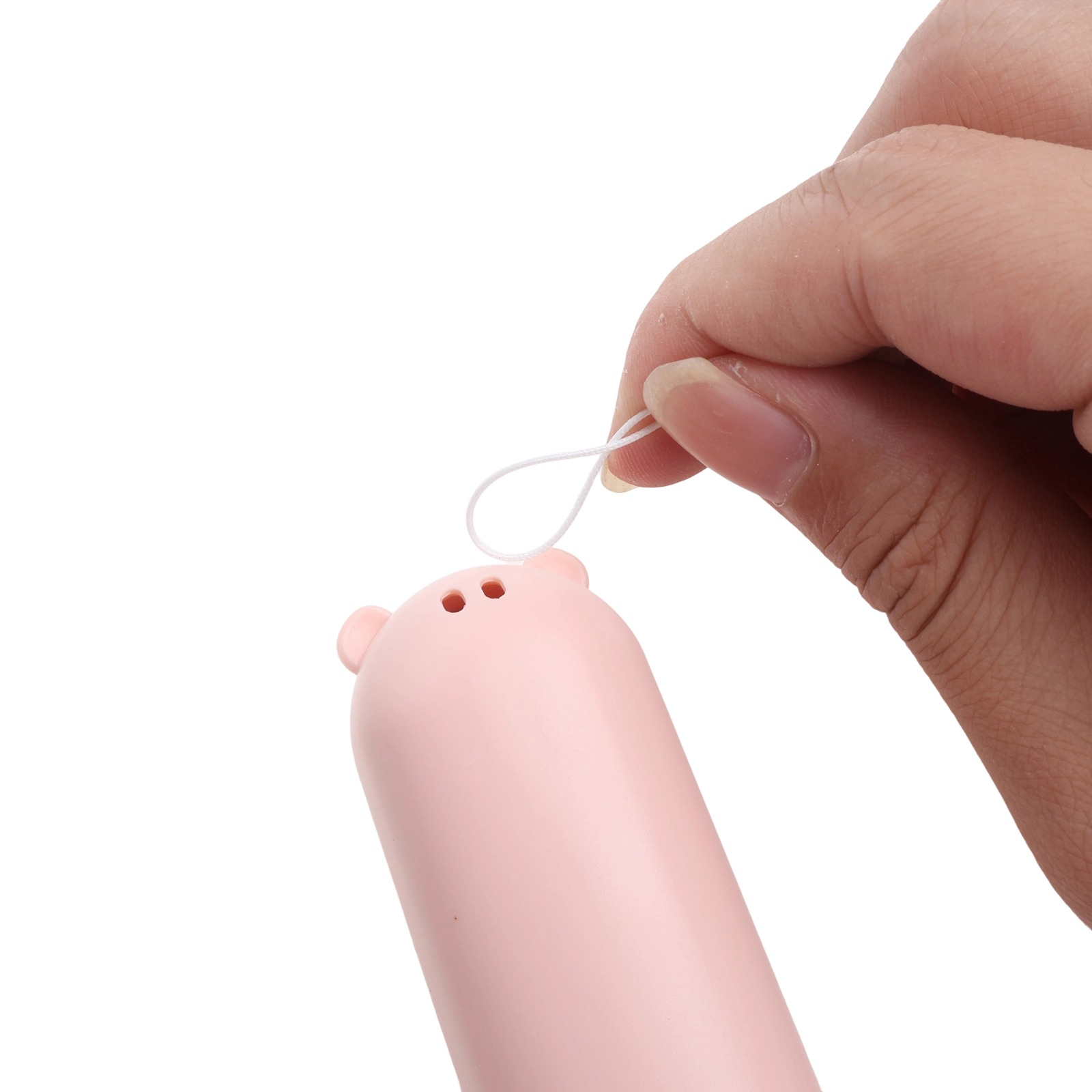 Eine Hand hält eine weiße Schnur, die an einem rosa Schweinchen-förmigen Objekt befestigt ist.