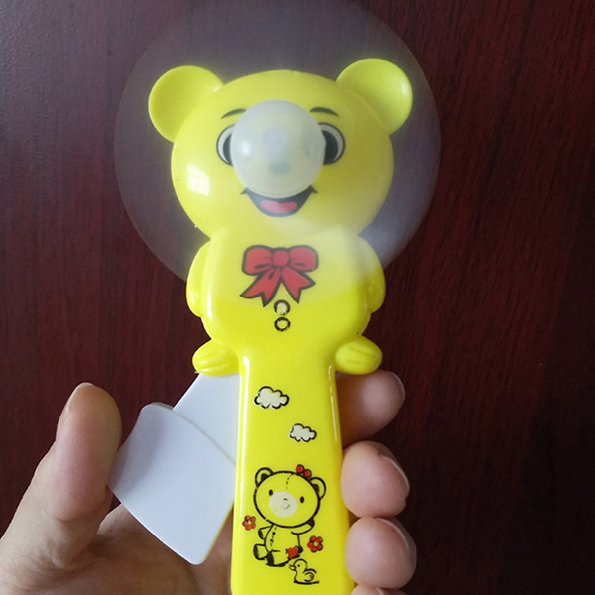 Gelber Teddybär-Ventilator mit rotem Schleifchen und Blasen auf Nase.