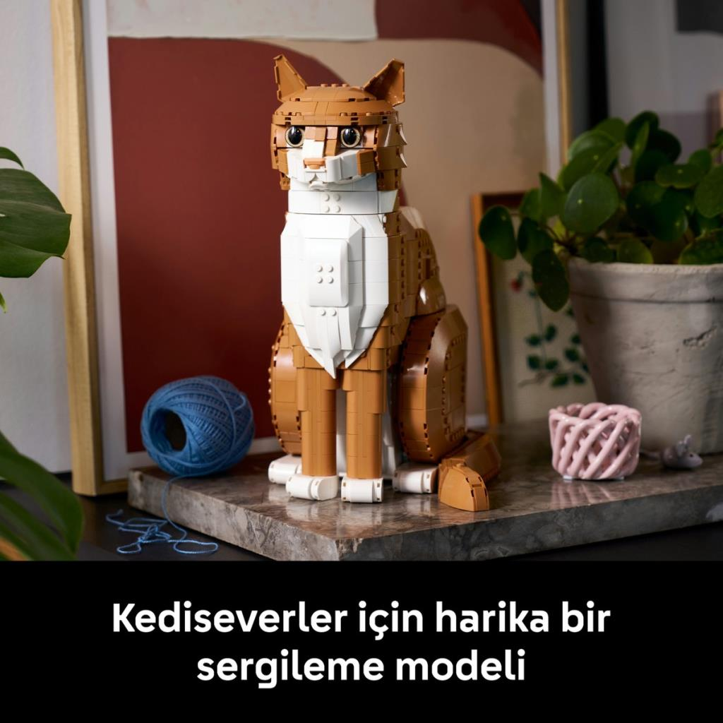 Kahverengi ve beyaz Lego kedi modeli, iplik ve bitkilerin olduğu mermer yüzeyde oturuyor.