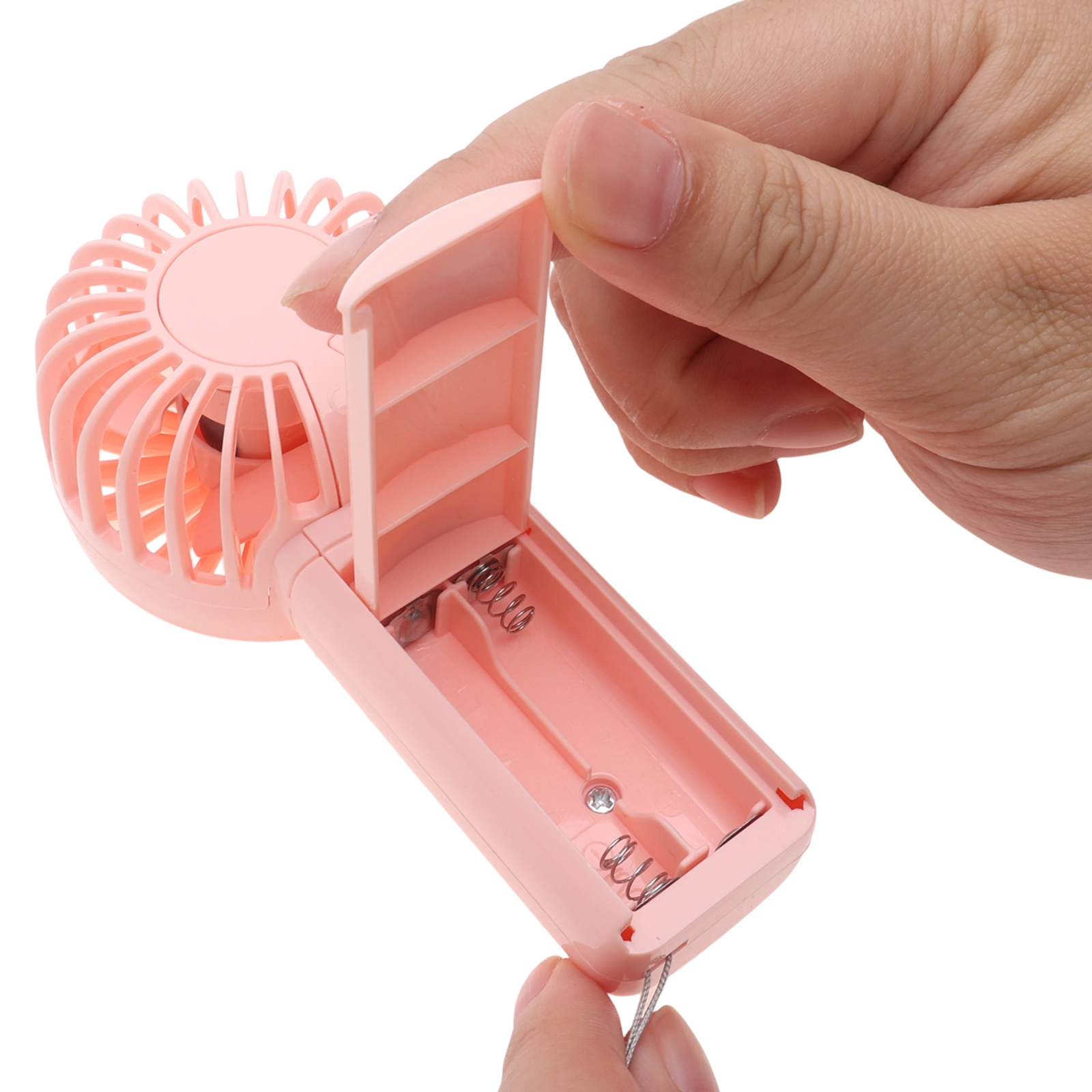 Eine Hand öffnet einen pinken tragbaren Ventilator und enthüllt das Batteriefach mit Federn.
