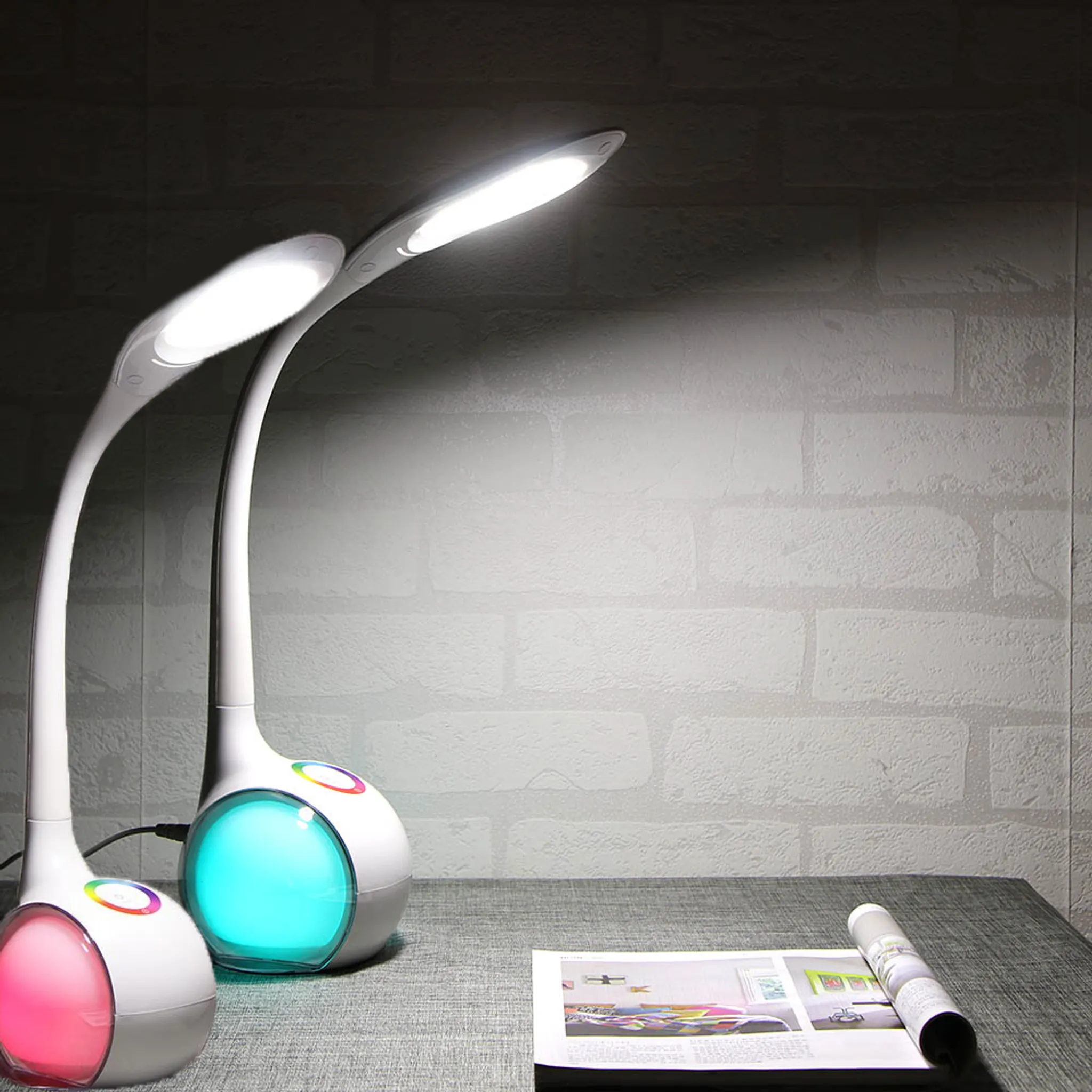 Zwei weiße Schreibtischlampen mit farbigen Lichtern auf einem Tisch.