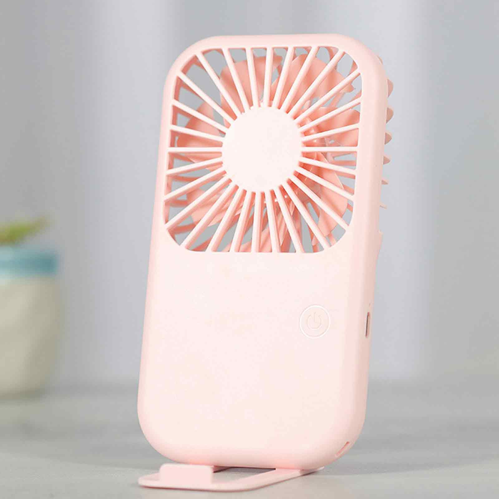 Ein kleiner rosa Ventilator mit Flügeln und einem Power-Symbol steht auf einem Tisch.