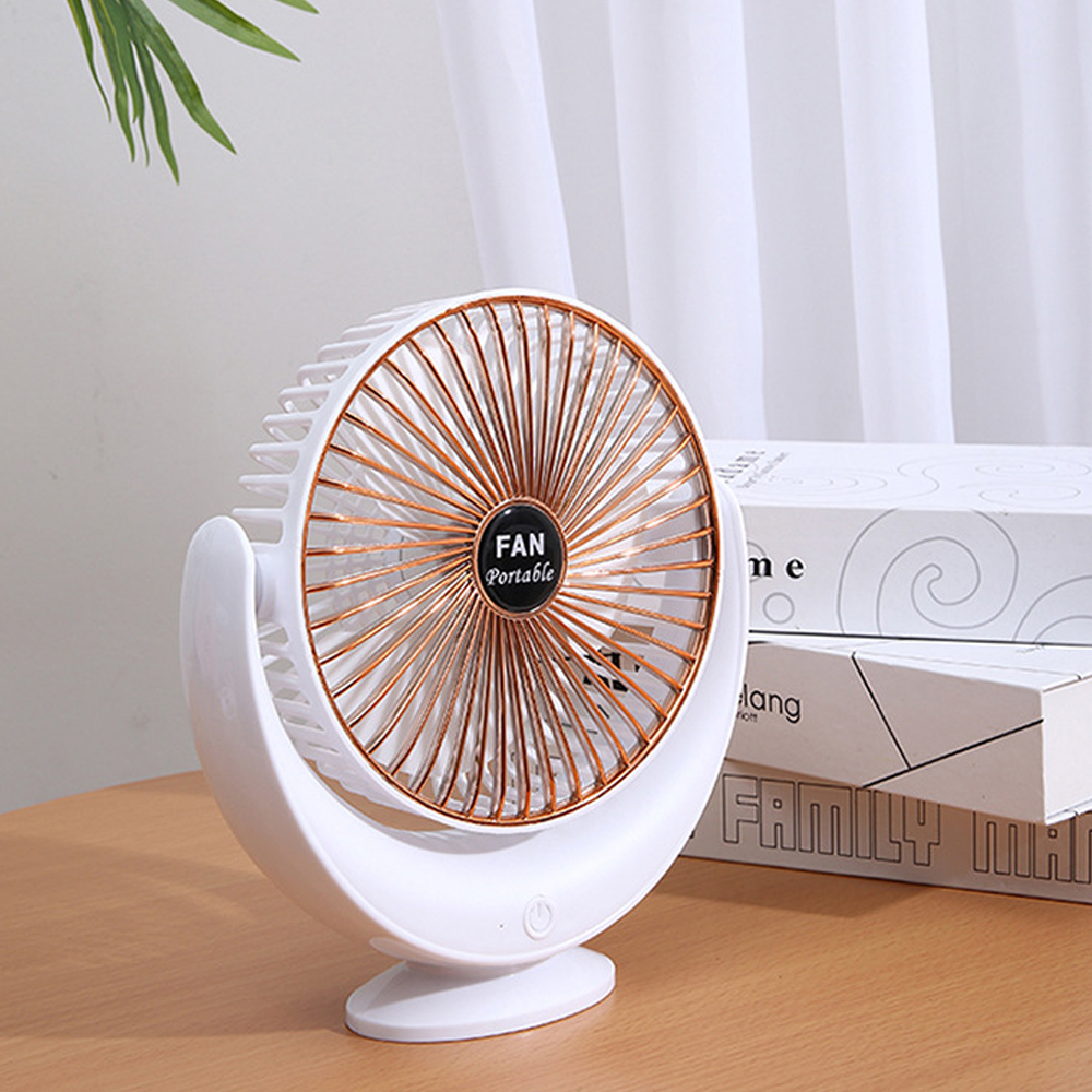 Ein weißer Tischventilator mit kupferfarbenen Streben steht auf einem Holztisch.