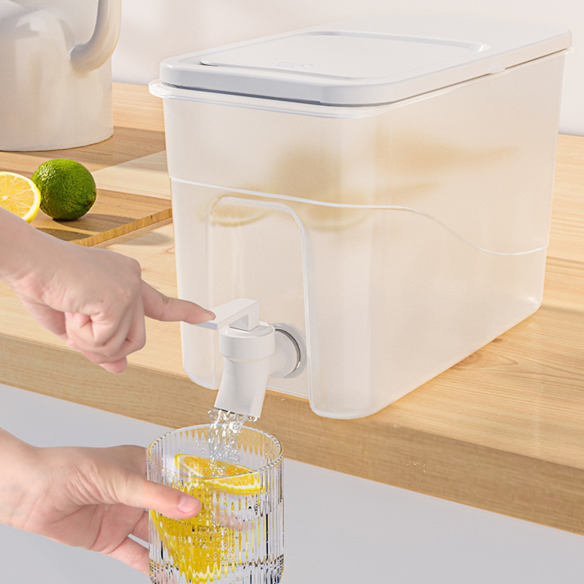 Eine Hand betätigt einen Zapfhahn, während Wasser in ein Glas mit Zitronenscheiben fließt.