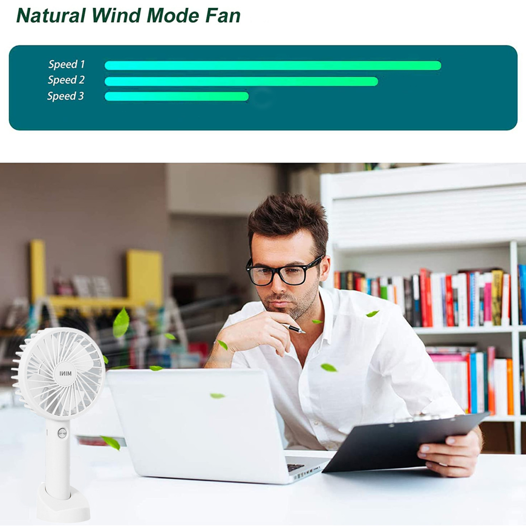 Ein Mann sitzt am Schreibtisch mit einem Laptop und einem kleinen Ventilator.
