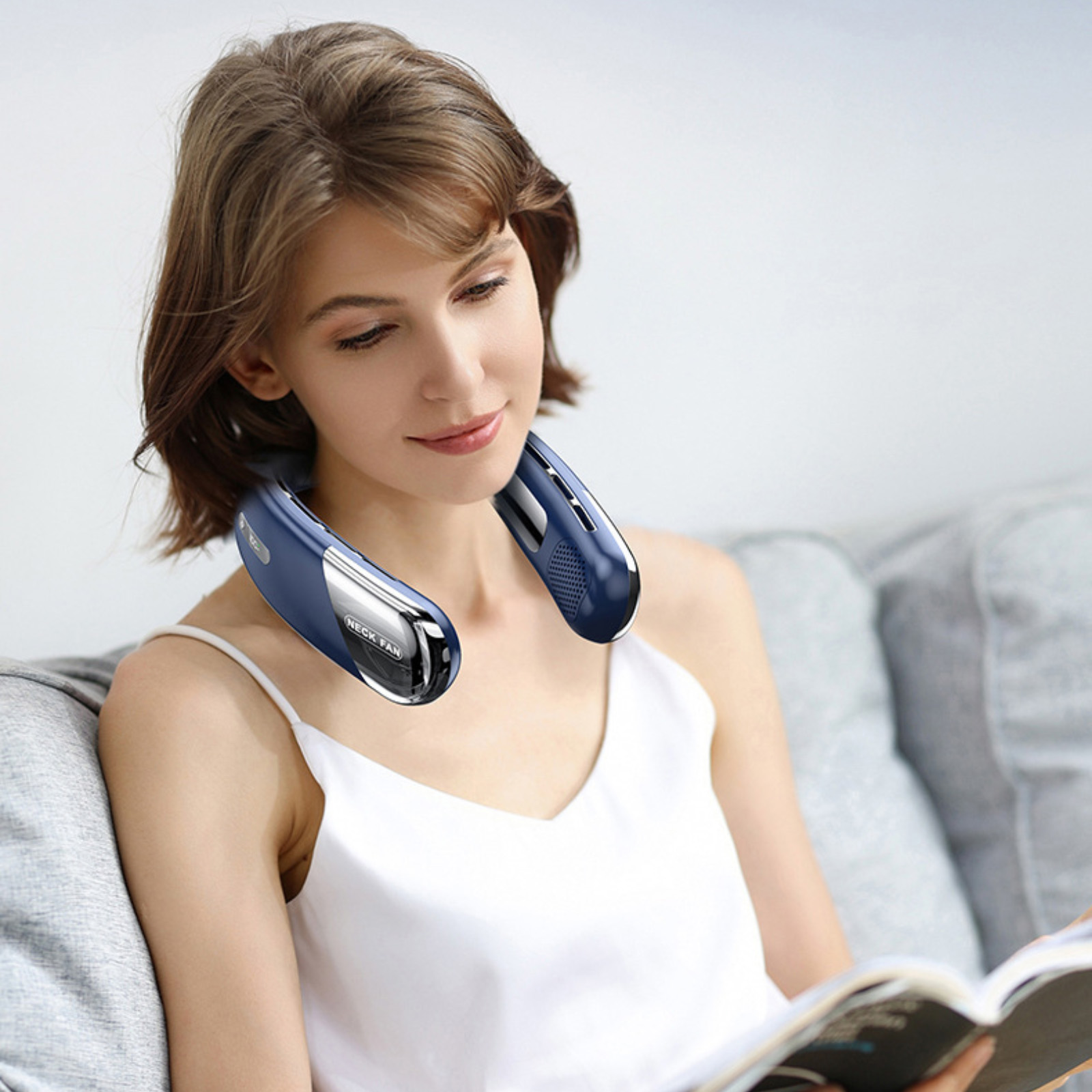 Eine Frau mit einem blauen Nackenventilator liest ein Buch.
