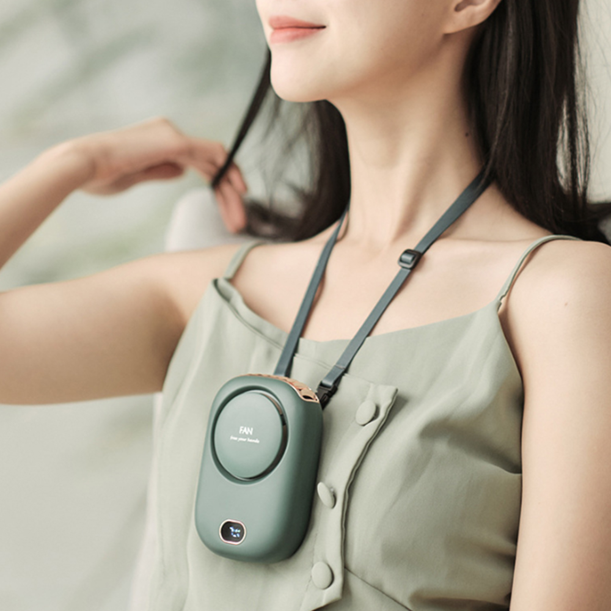 Eine Frau trägt einen grünen Anhänger-Ventilator um den Hals, der an einem Band befestigt ist.