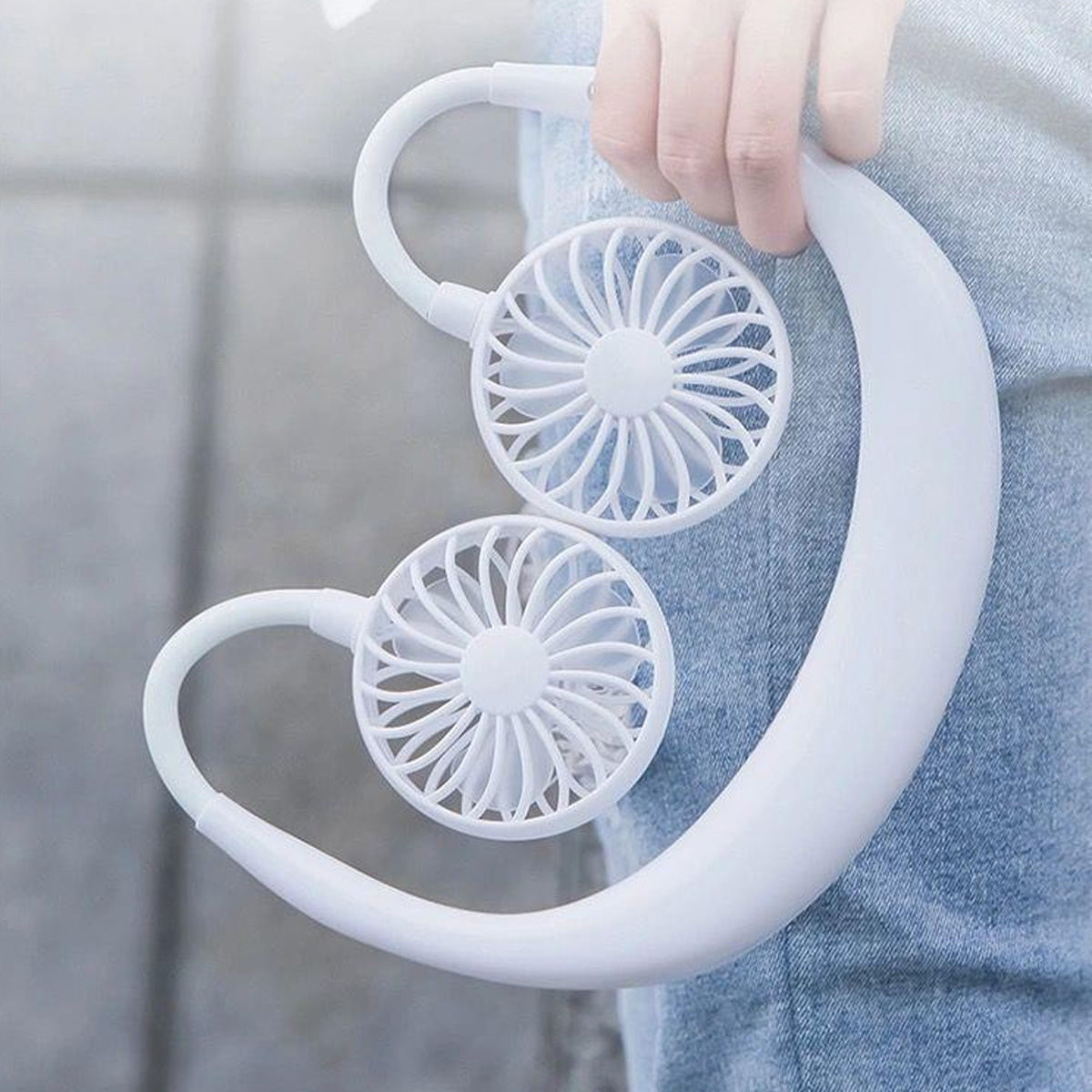 Eine weiße Nackenventilator mit zwei Lüftern, der von einer Hand gehalten wird.