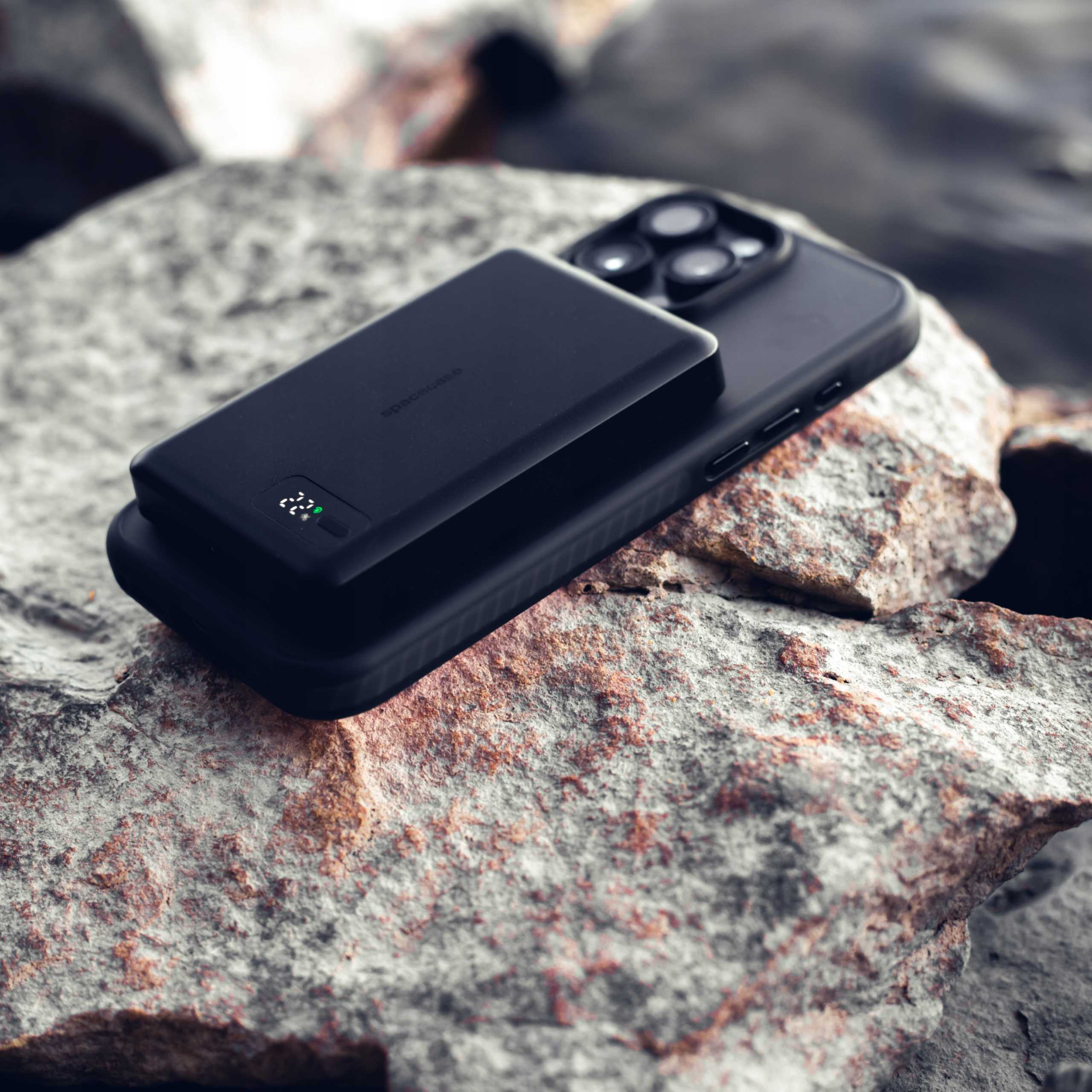 Czarny smartfon z powerbankiem na skałach.