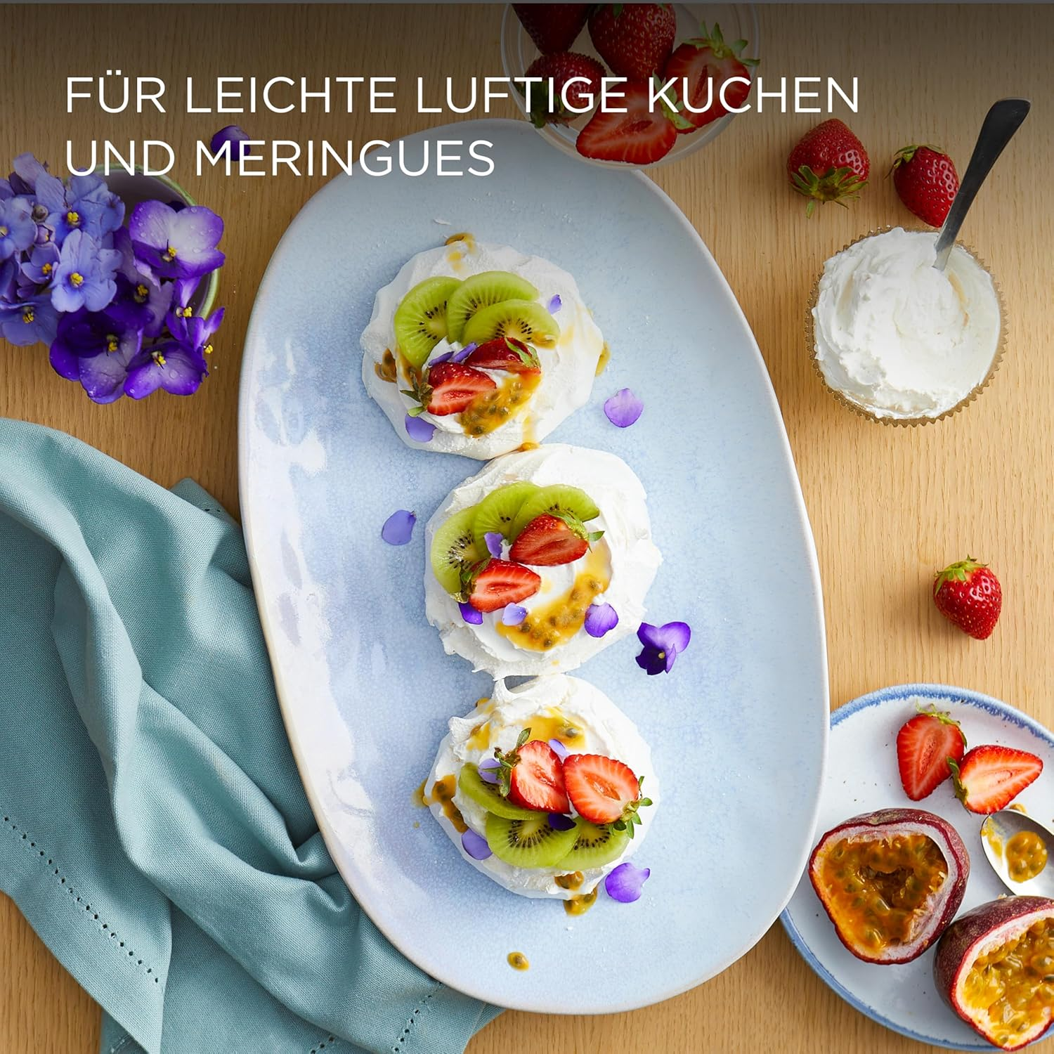 Pavlovas mit Kiwi, Erdbeeren und Maracuja, garniert mit essbaren Blüten.