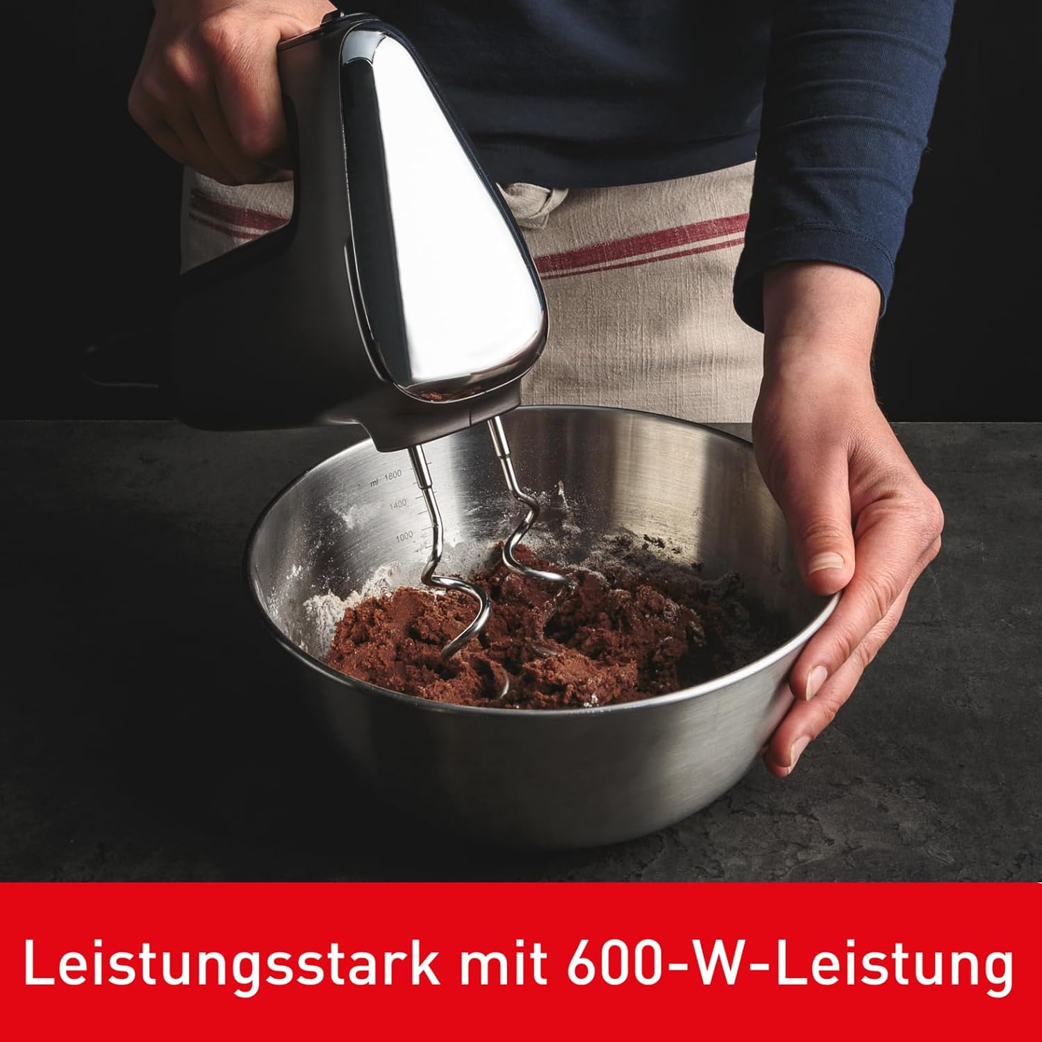 Eine Hand hält einen Handmixer über einer Schüssel mit Teig.