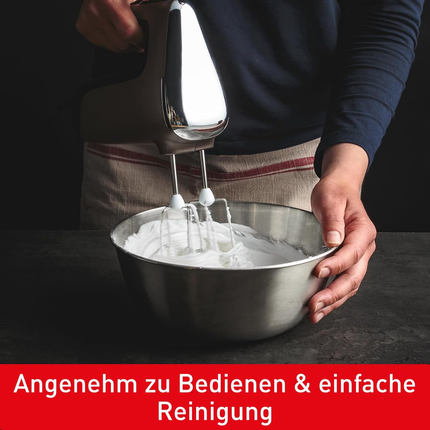 Eine Hand hält einen Mixer über eine Schüssel Schlagsahne, darunter ein rotes Banner.