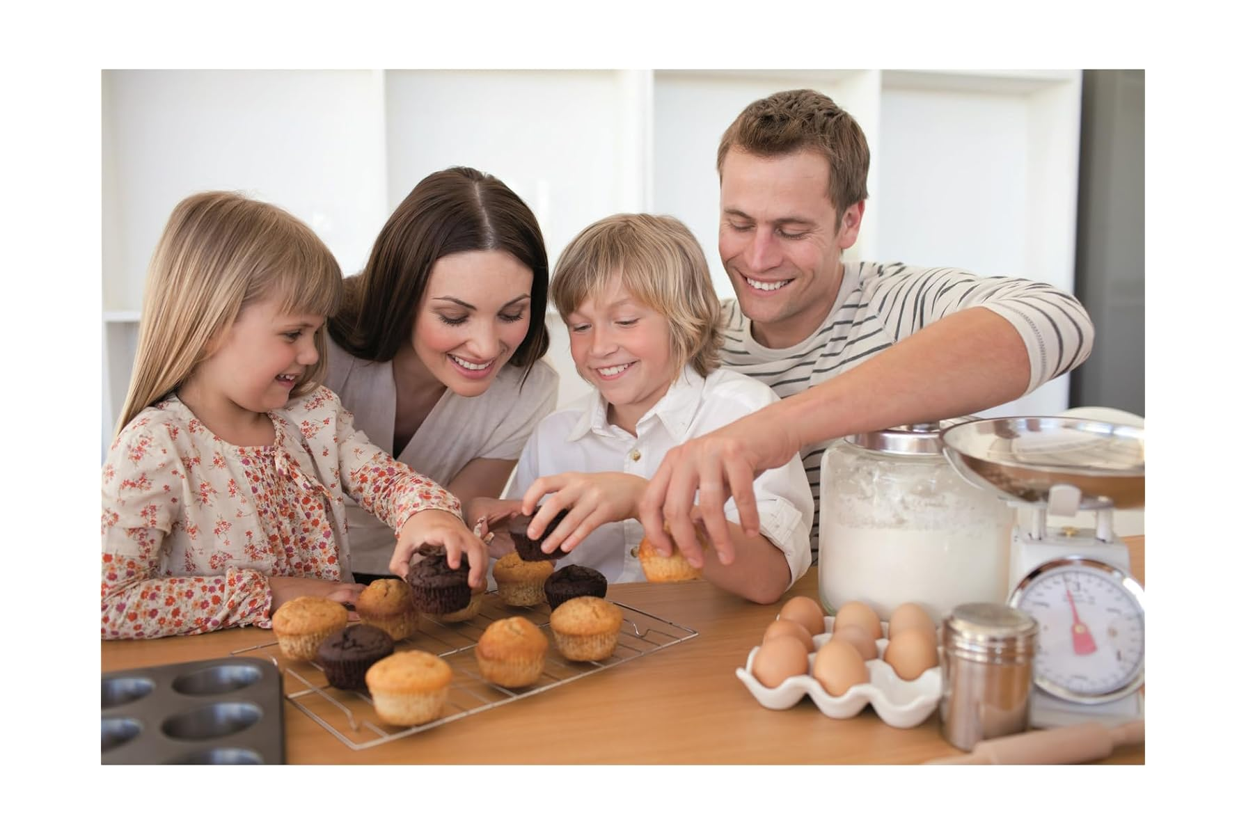 Eine Familie backt Muffins. Sie lächeln und nehmen die Muffins vom Rost.