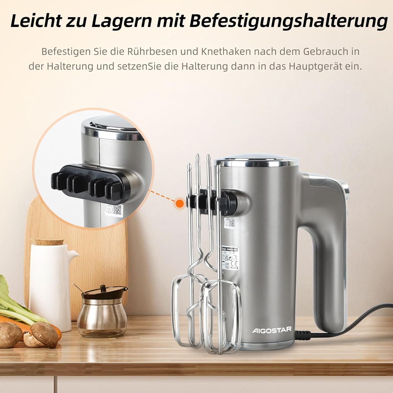 Grauer Handmixer mit Zubehör und Zutaten auf einer Arbeitsplatte.