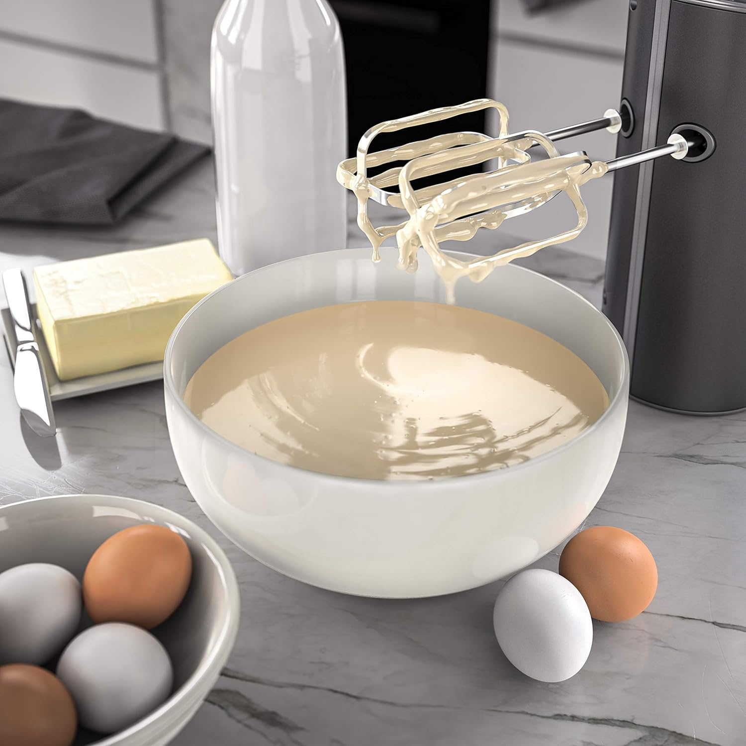 Rührschüssel mit Teig, Eiern, Butter und Milch. Handmixer mit Teig auf den Rührbesen.