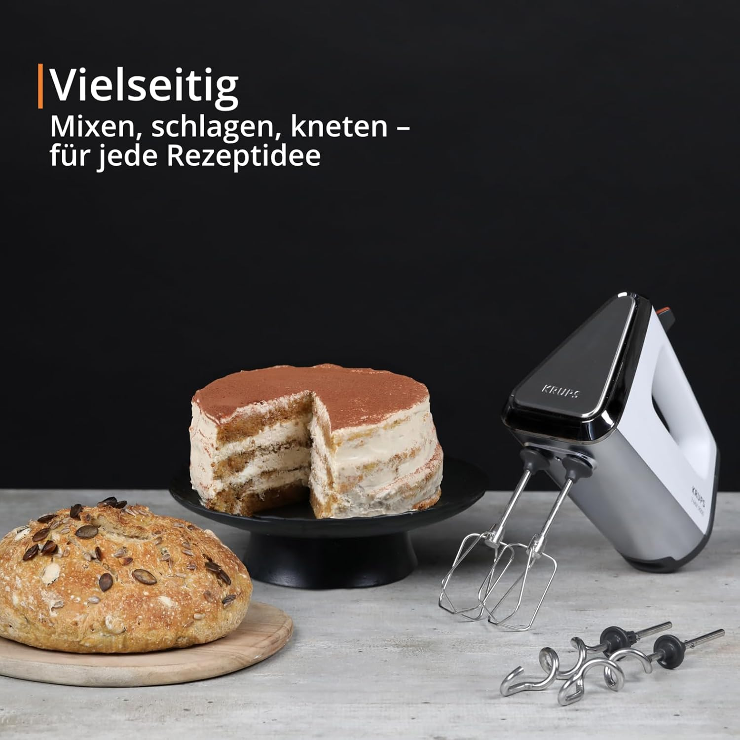 Ein Handmixer, ein Brot und ein Kuchen auf einem Tisch.