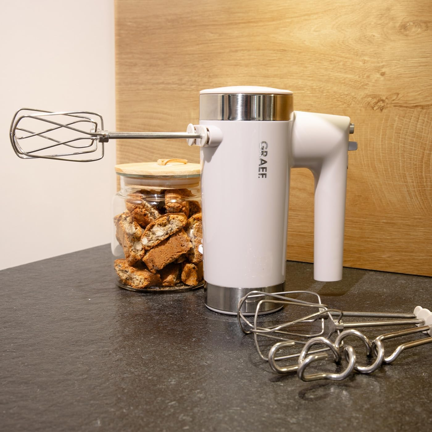 Ein weißer Graef Handmixer mit einem angebrachten Quirl, neben einem Glas Kekse.