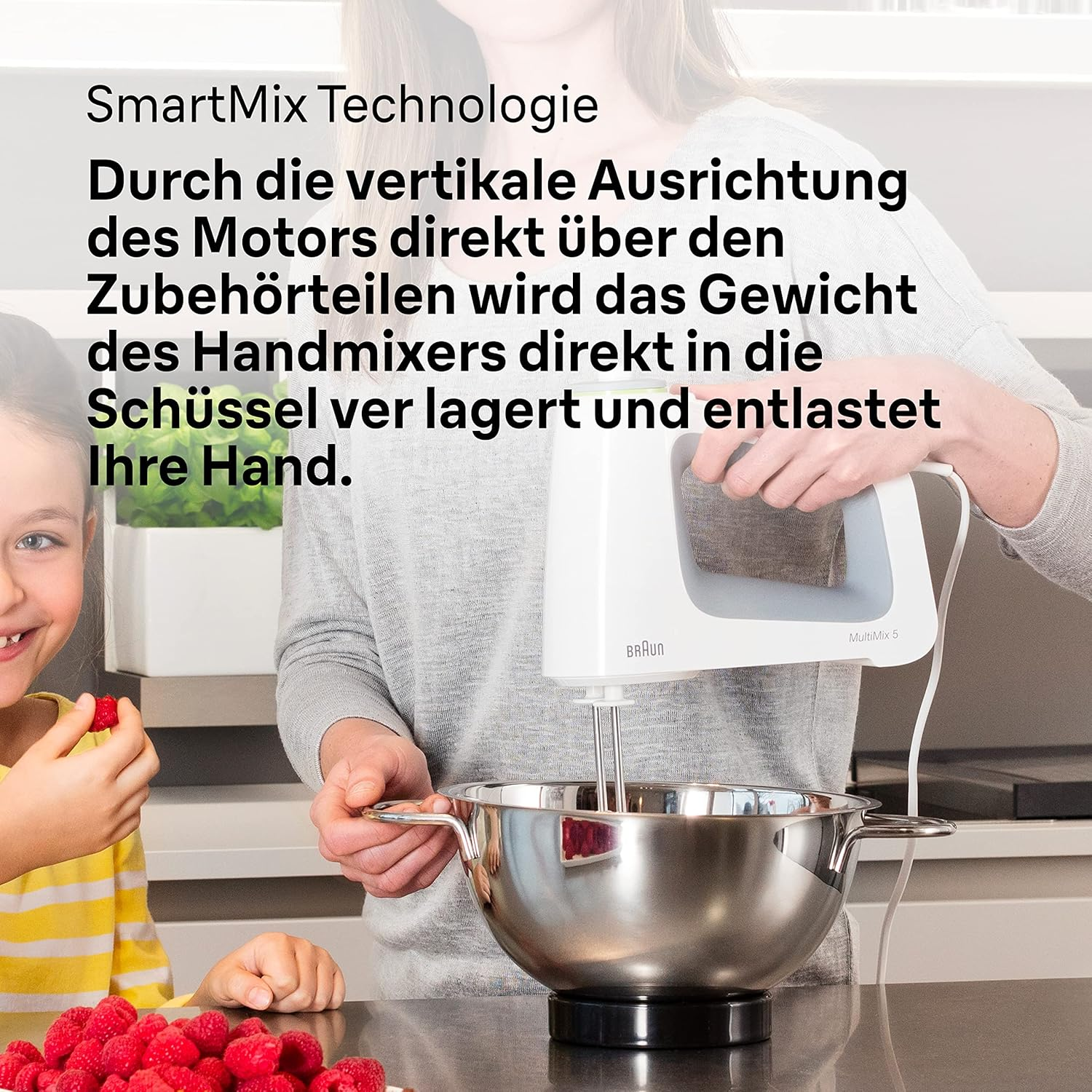 Personen benutzen einen Handmixer über einer Rührschüssel, daneben Himbeeren.