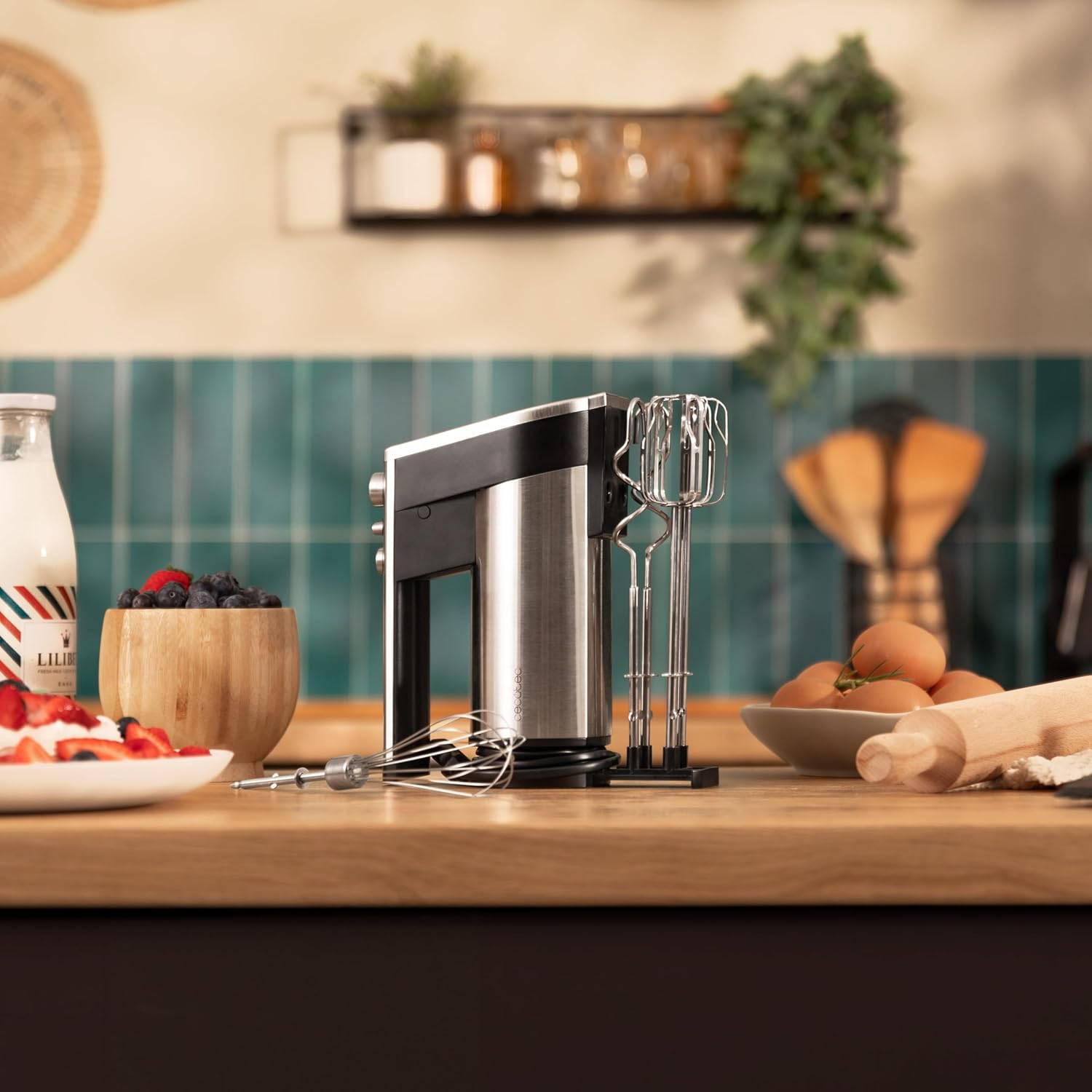 Ein Handmixer steht auf einer Arbeitsplatte neben Beeren, Eiern und einem Nudelholz.