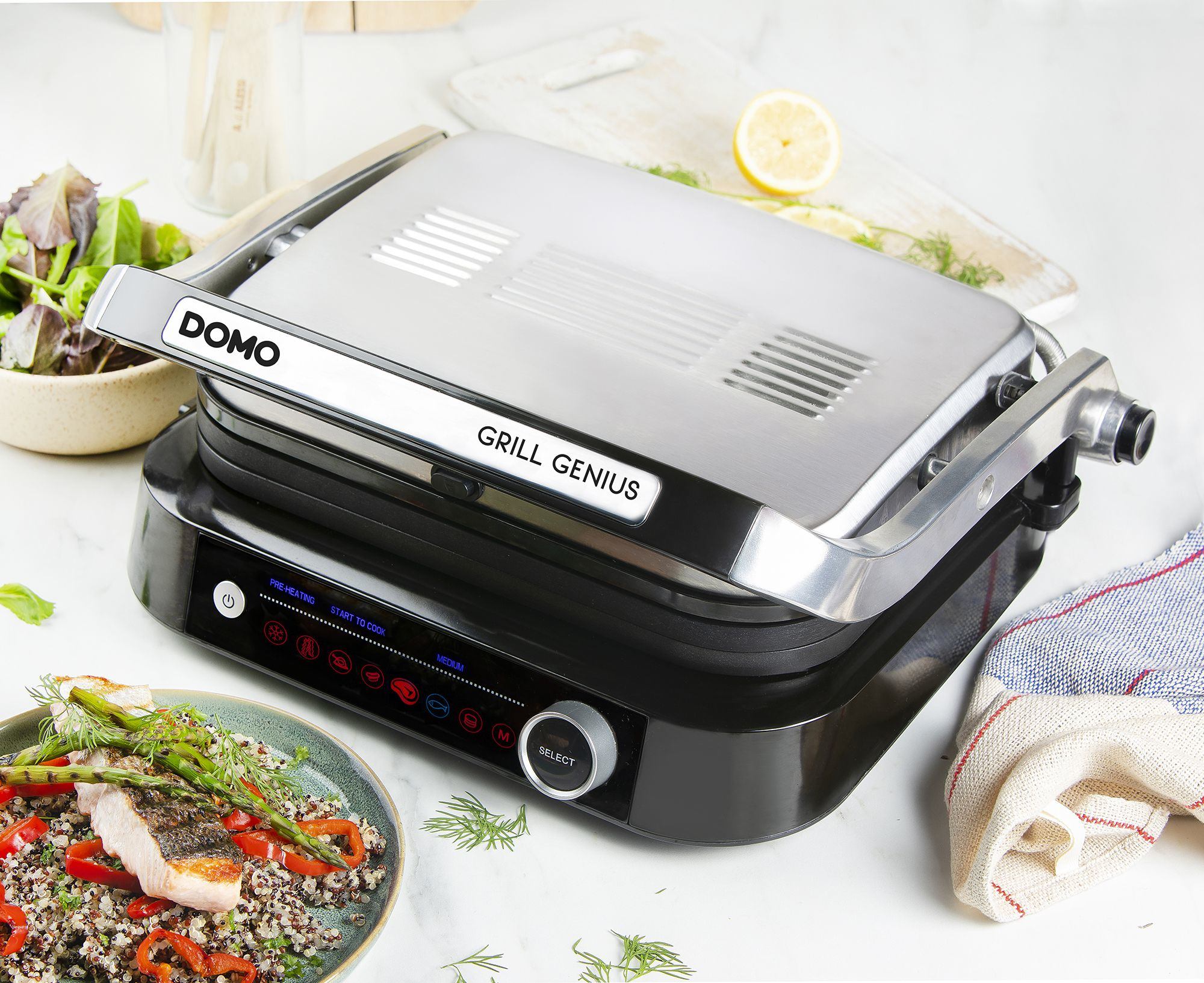 Ein offener Grill mit einem Teller Lachs und Gemüse daneben.