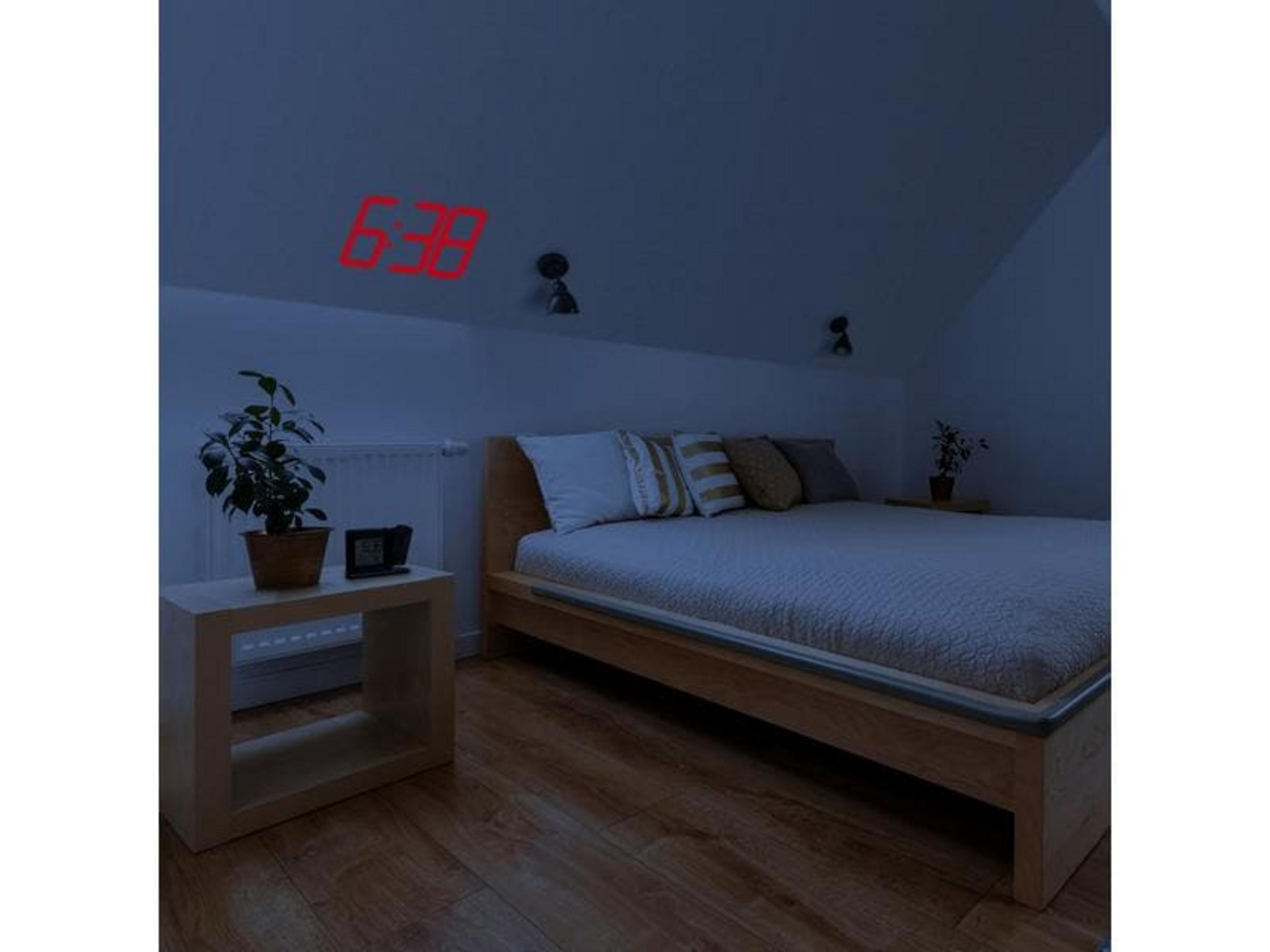 Rote digitale Anzeige 6:38 an der Decke über einem Bett.