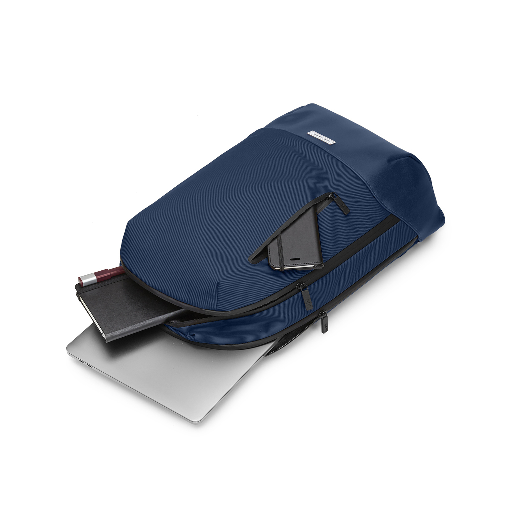 Zaino blu scuro con scomparto aperto, laptop, taccuino e penna.