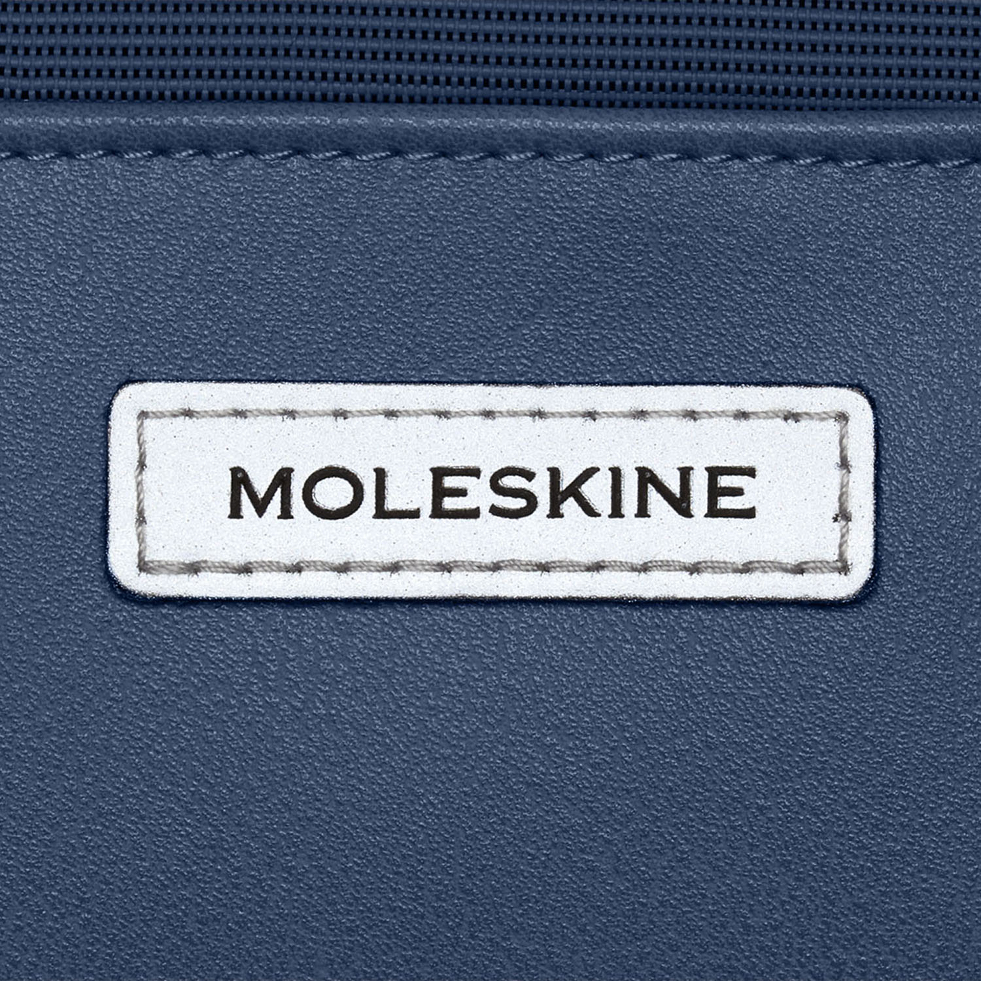 Un'etichetta bianca con la scritta "MOLESKINE" su materiale testurizzato blu scuro.