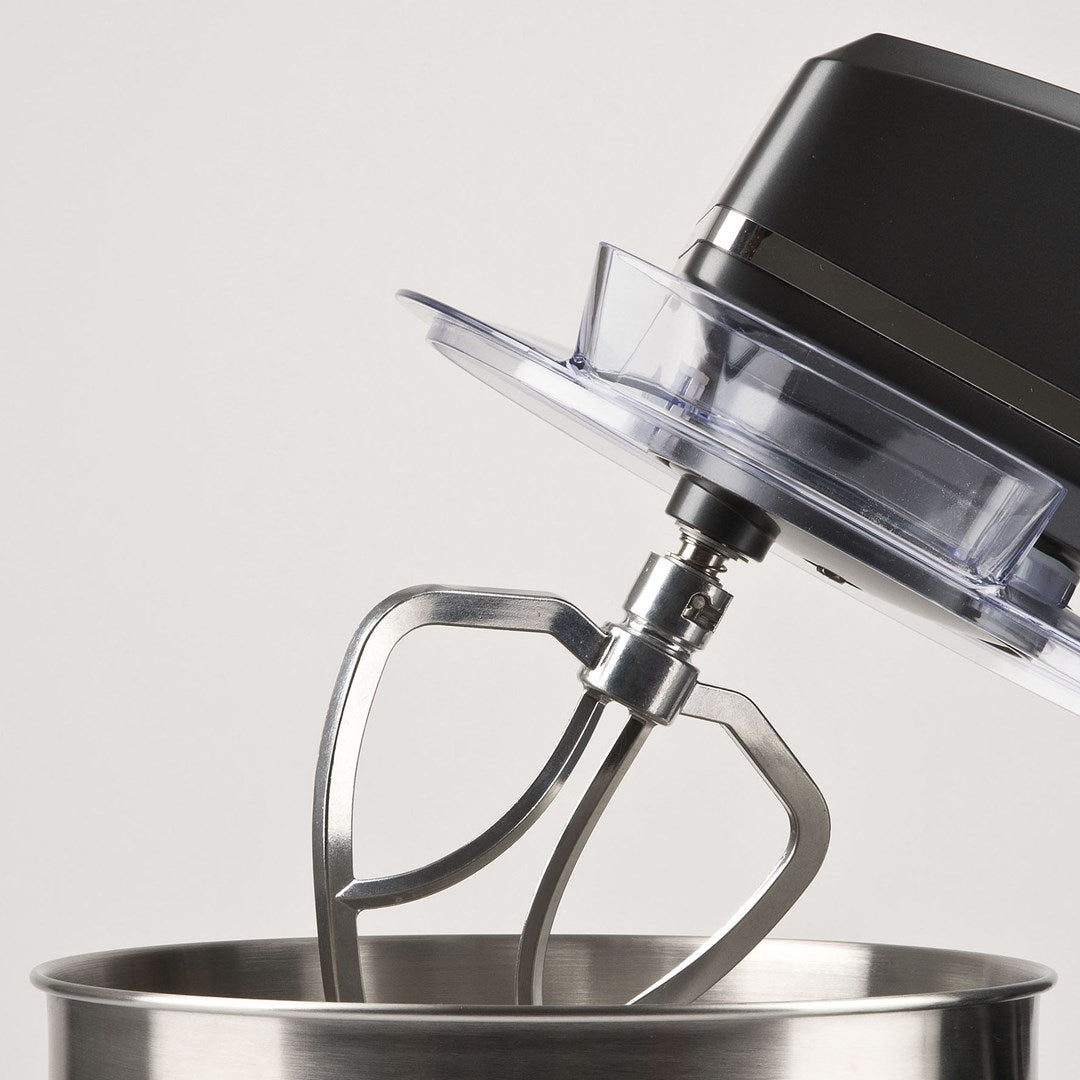 Primo piano di un impastatore nero con frusta in metallo in ciotola inox.
