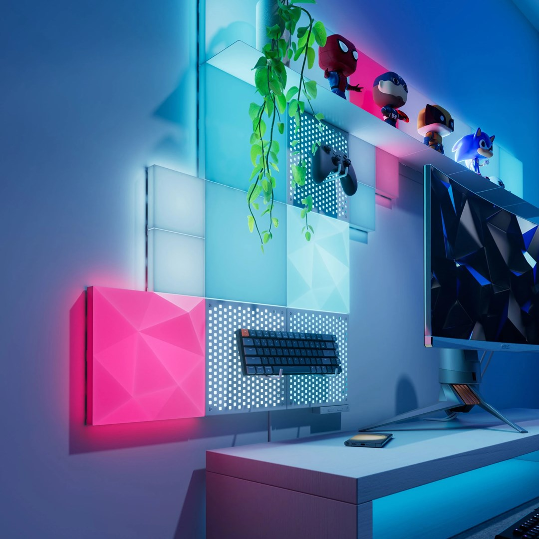 Scrivania da gamer con luci colorate, tastiera, controller, action figure e monitor.