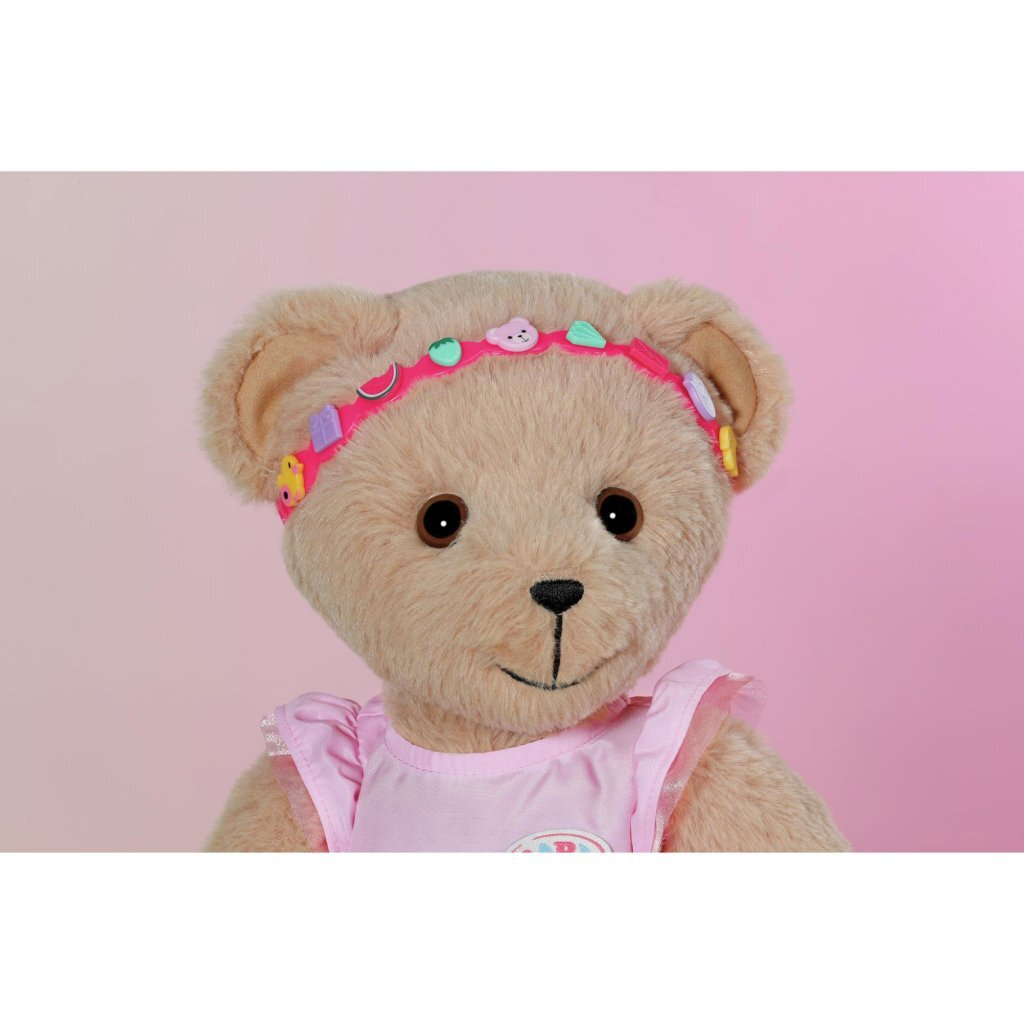 Un orsacchiotto con fascia rosa con ciondoli e vestito rosa.