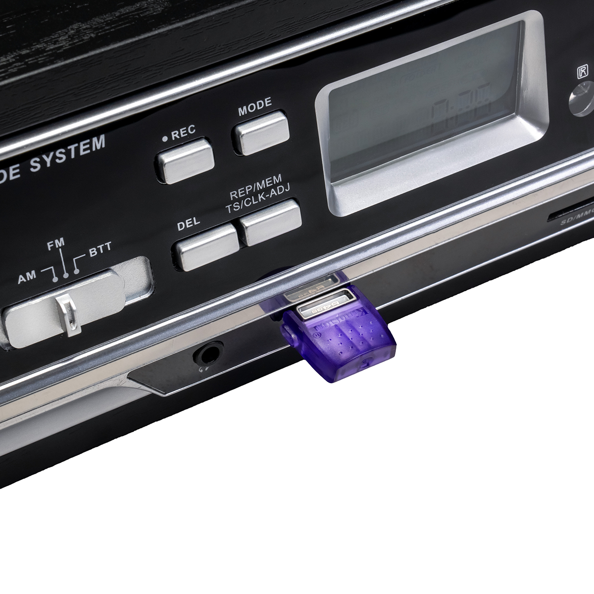 Fioletowy pendrive jest podłączony do czarnego urządzenia audio z srebrnymi przyciskami i wyświetlaczem.