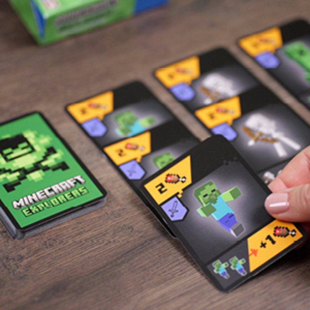 Cartes Minecraft Explorers sur une table en bois, une main tient une carte avec un zombie.