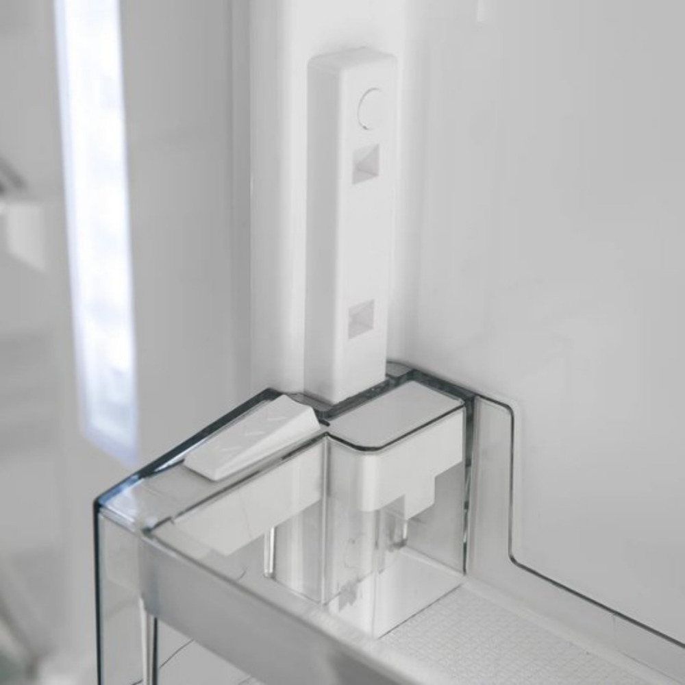 Close-up of a white ice maker bin inside a refrigerator.