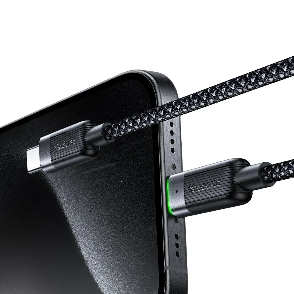 Siyah bir USB-C kablosu, yeşil ışıklı siyah bir akıllı telefona takılıyor.
