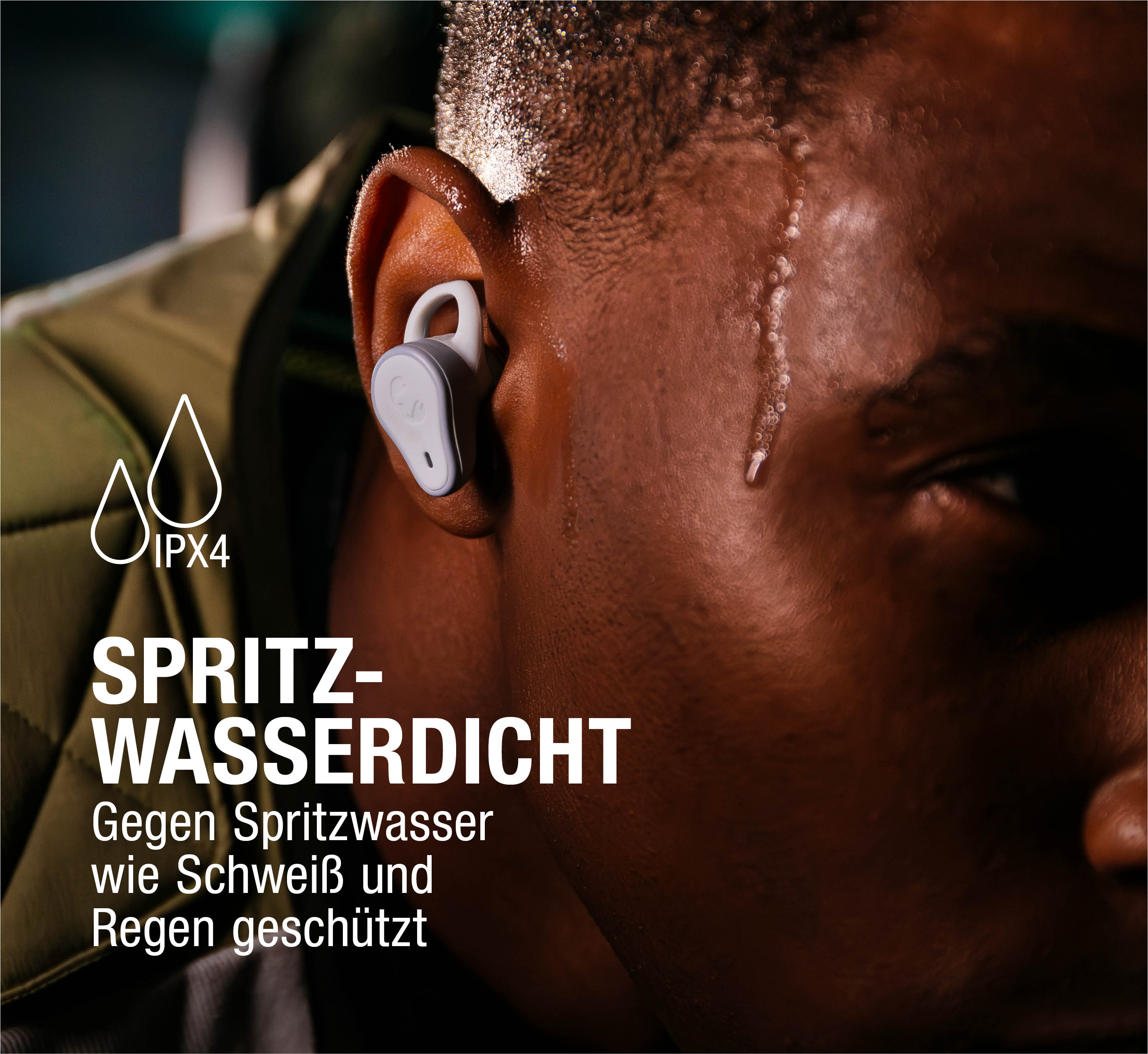Ein Mann mit Schweiß auf der Stirn trägt Ohrhörer. IPX4 Wasserdicht.